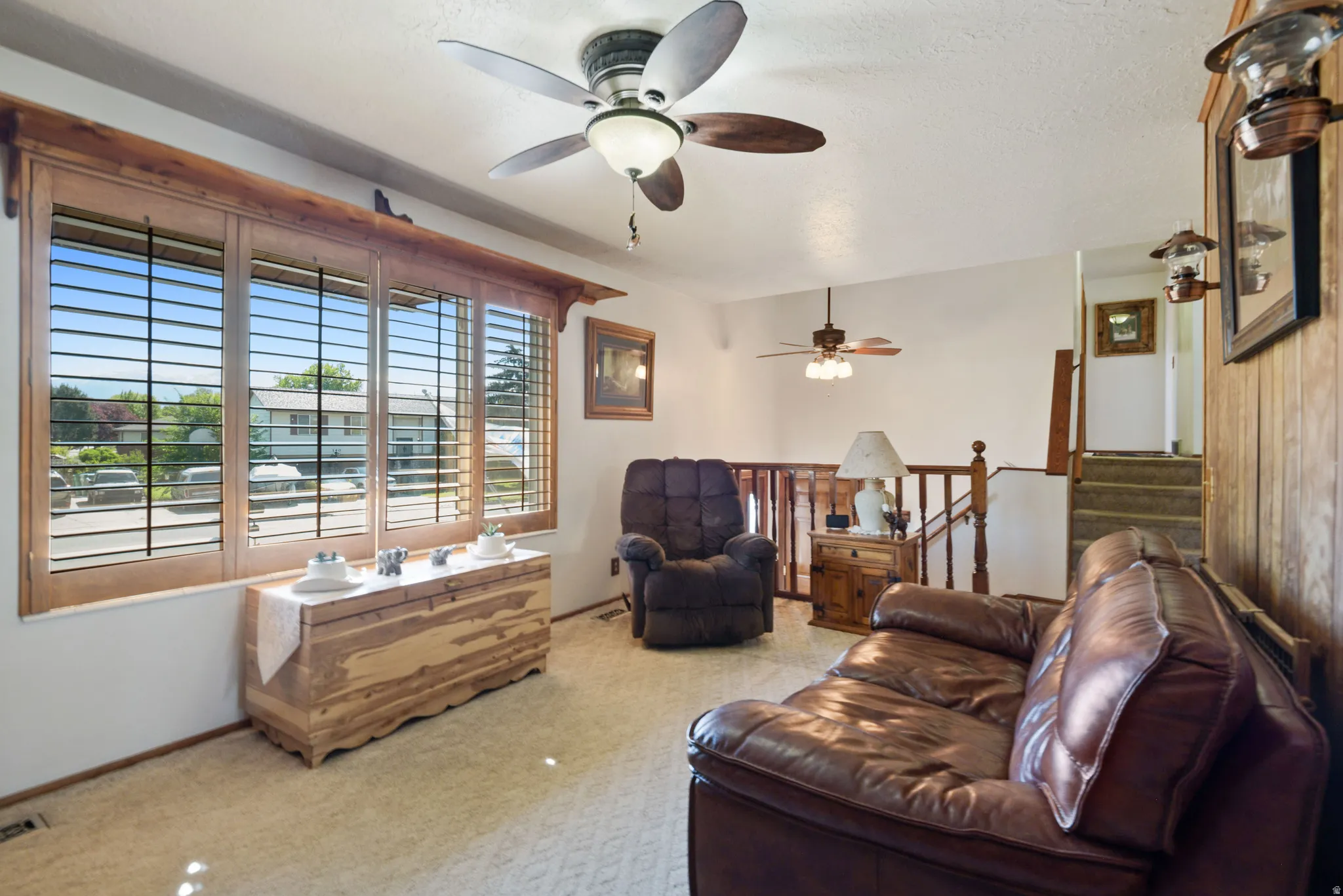 Living room with ceiling fan, carpet floors, and a textured ceiling