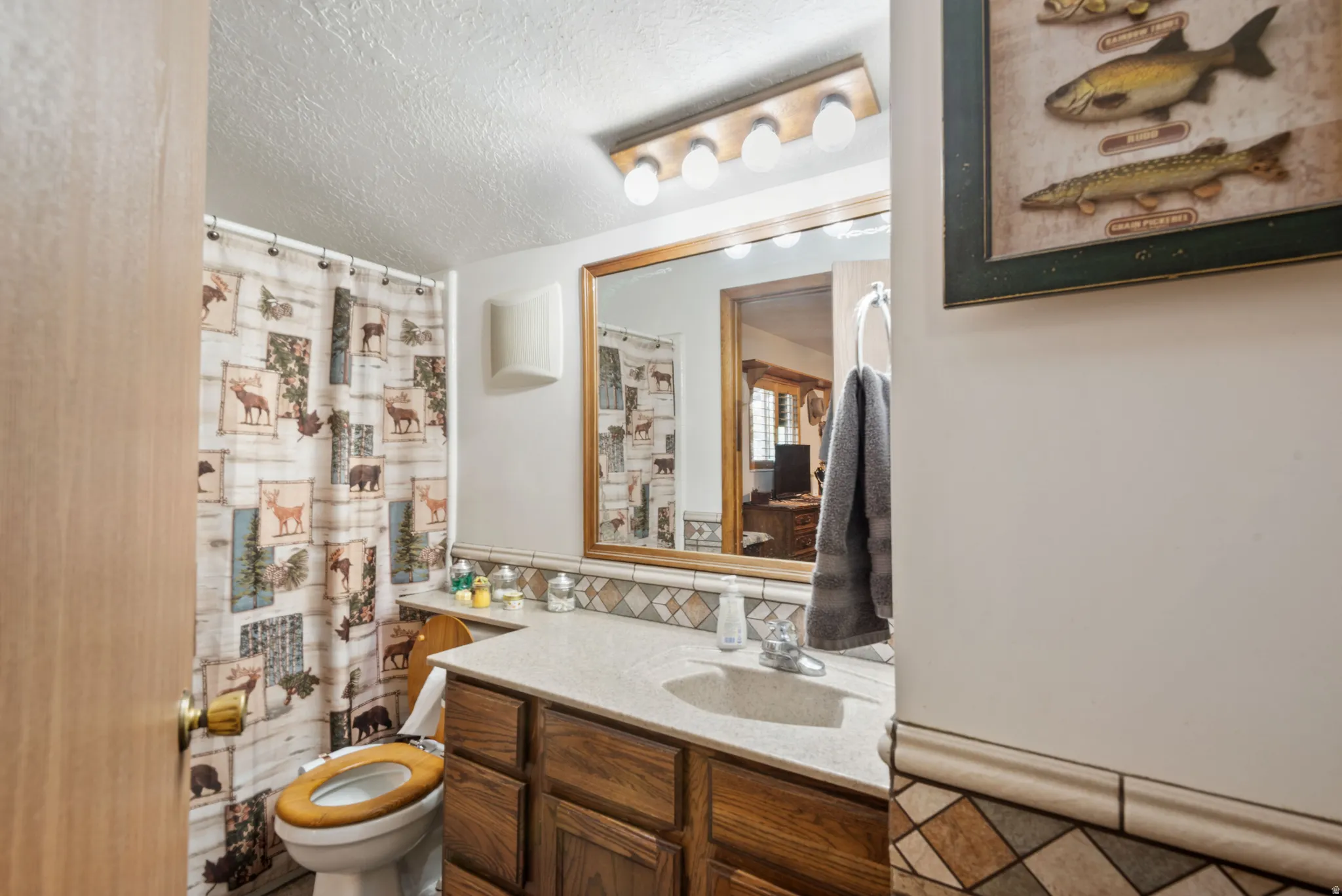 Full bath featuring a shower with shower curtain, vanity, a textured ceiling, and decorative backsplash