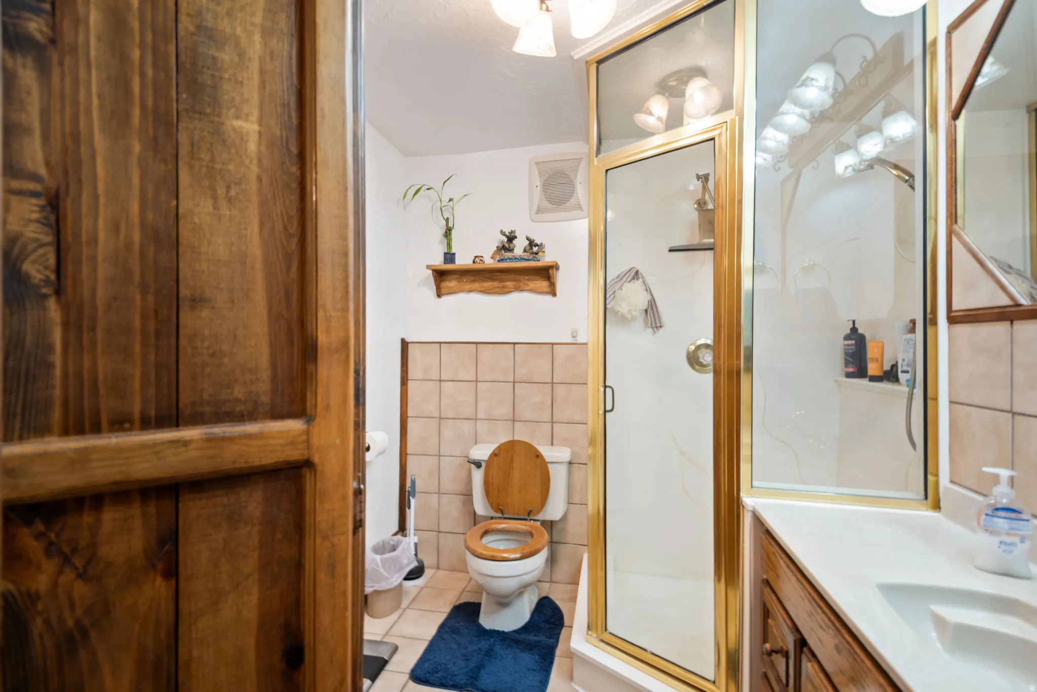 Full bath with vanity, a shower stall, tile walls, and light tile patterned floors