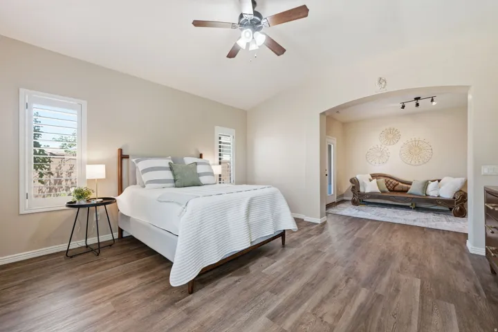 Spacious room featuring wood-finish flooring, vaulted ceiling, and an arched entry to an adjoining alcove