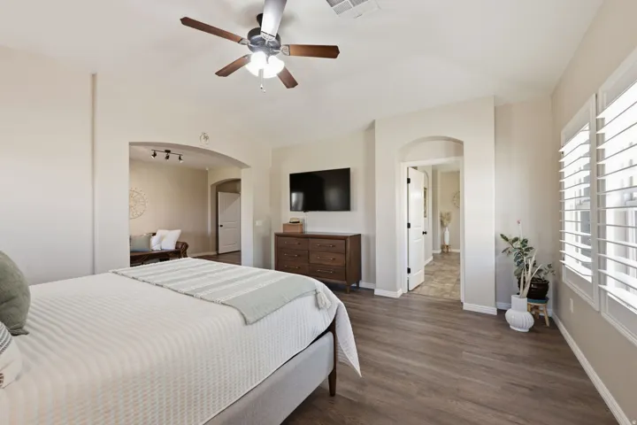 Wood-finish flooring throughout, complemented by arched doorways and ceiling fan