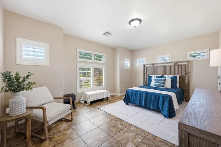 Spacious room featuring tile flooring, multiple windows with white plantation shutters, and a semi-flush mount ceiling light