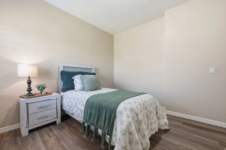 Bedroom featuring neutral wall paint, wood-finish flooring, and white baseboards
