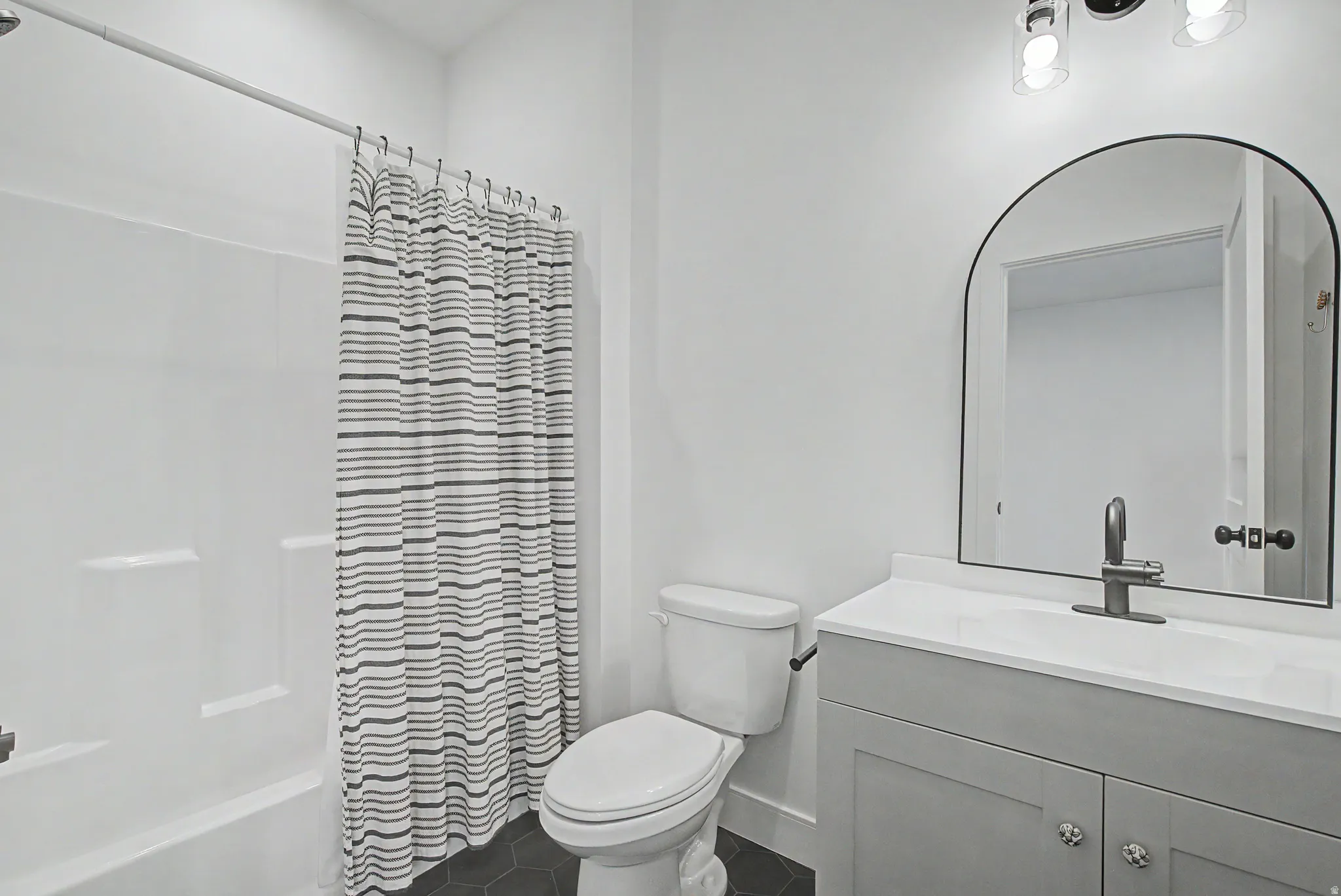 Full bathroom featuring vanity, shower / tub combo, and dark tile patterned flooring