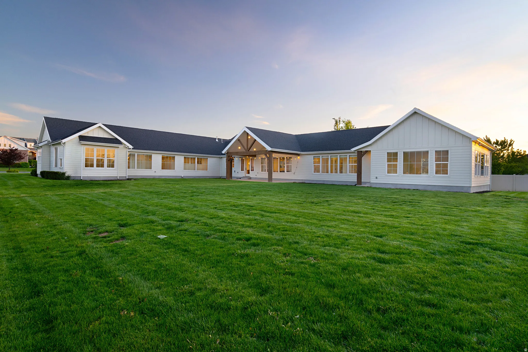 Modern farmhouse style home with board and batten siding, a yard, and a patio area