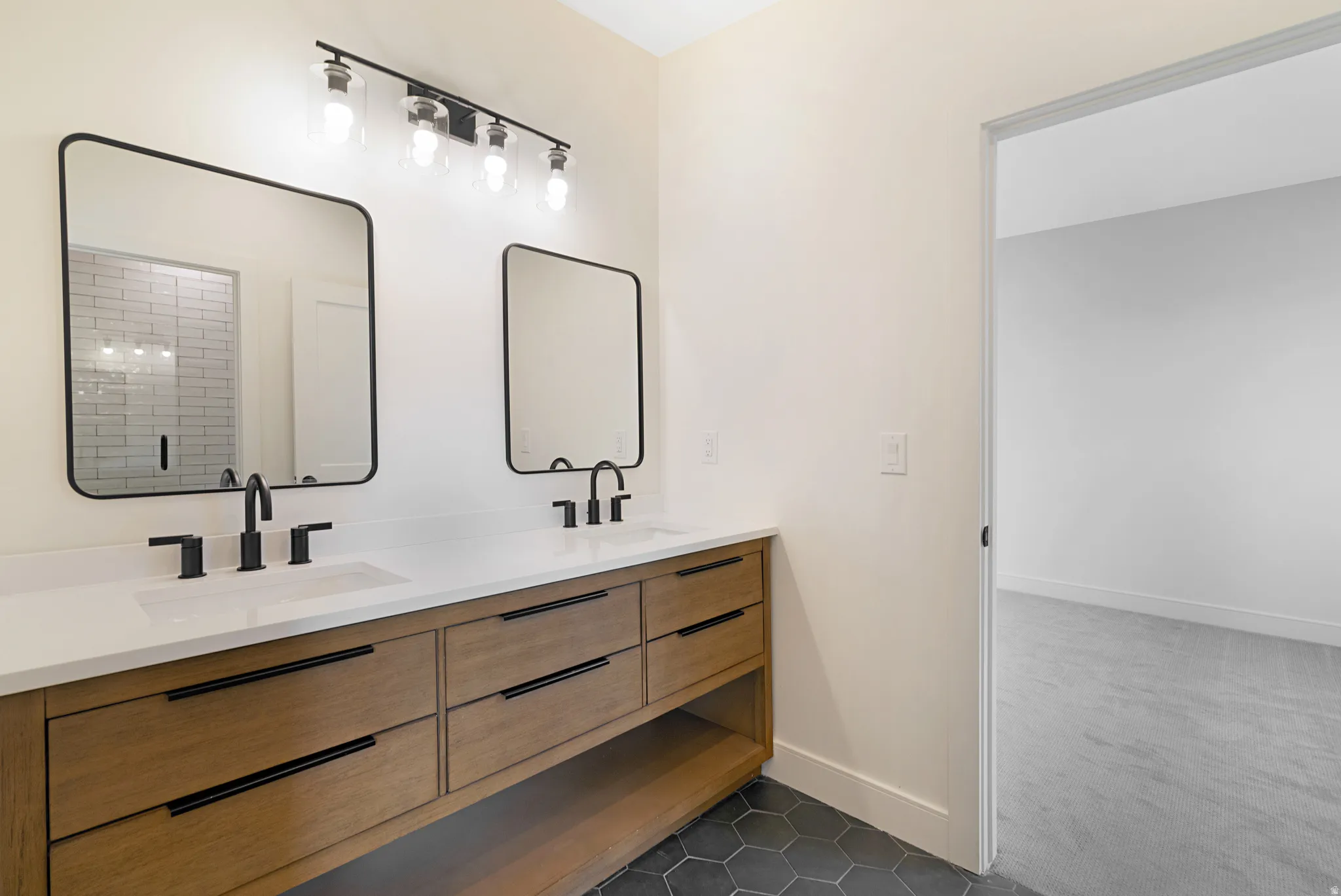 Full bathroom featuring double vanity, dark tile patterned flooring, and dark carpet