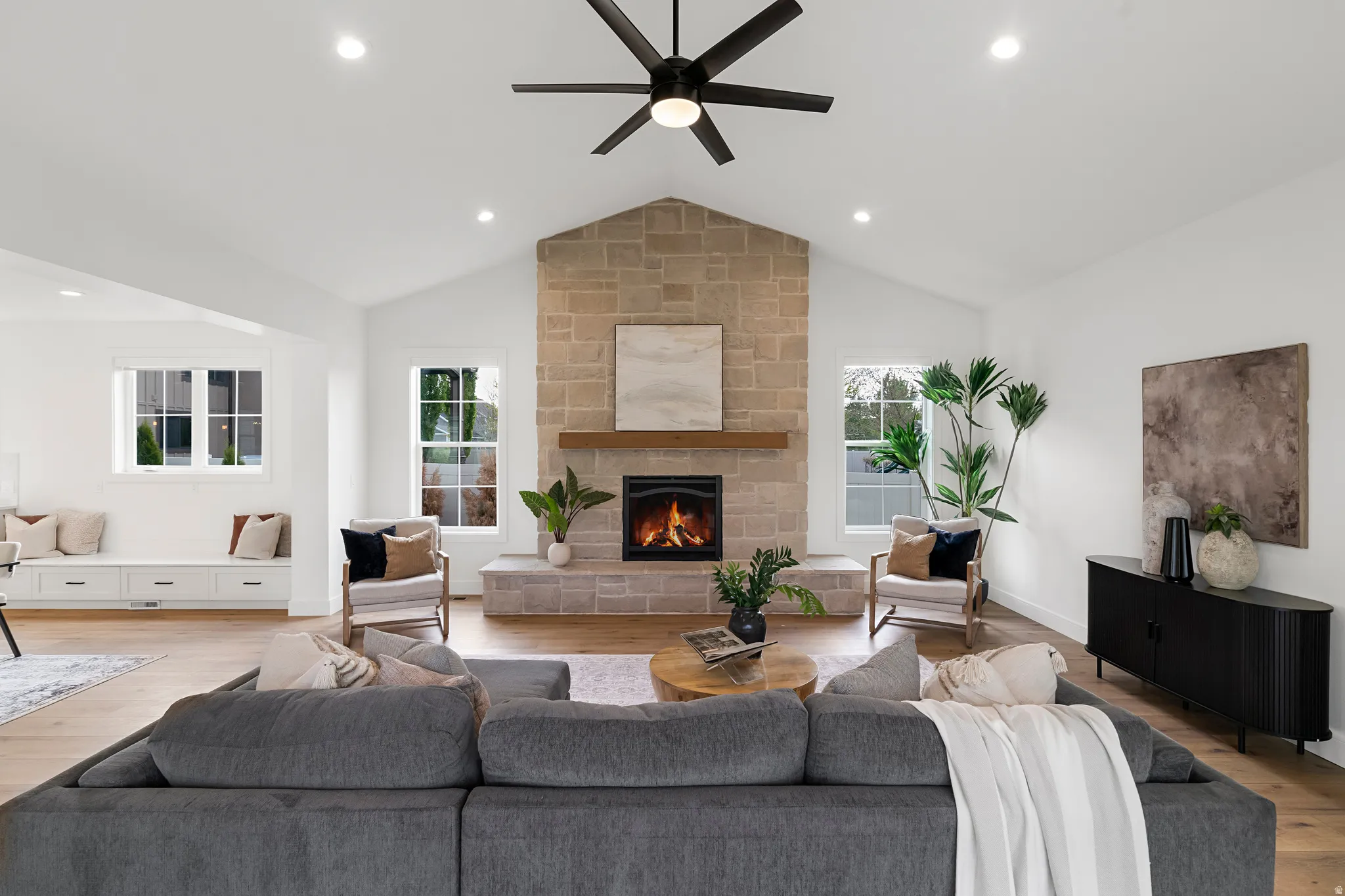 Living area with a ceiling fan, wood finished floors, a stone fireplace, and recessed lighting