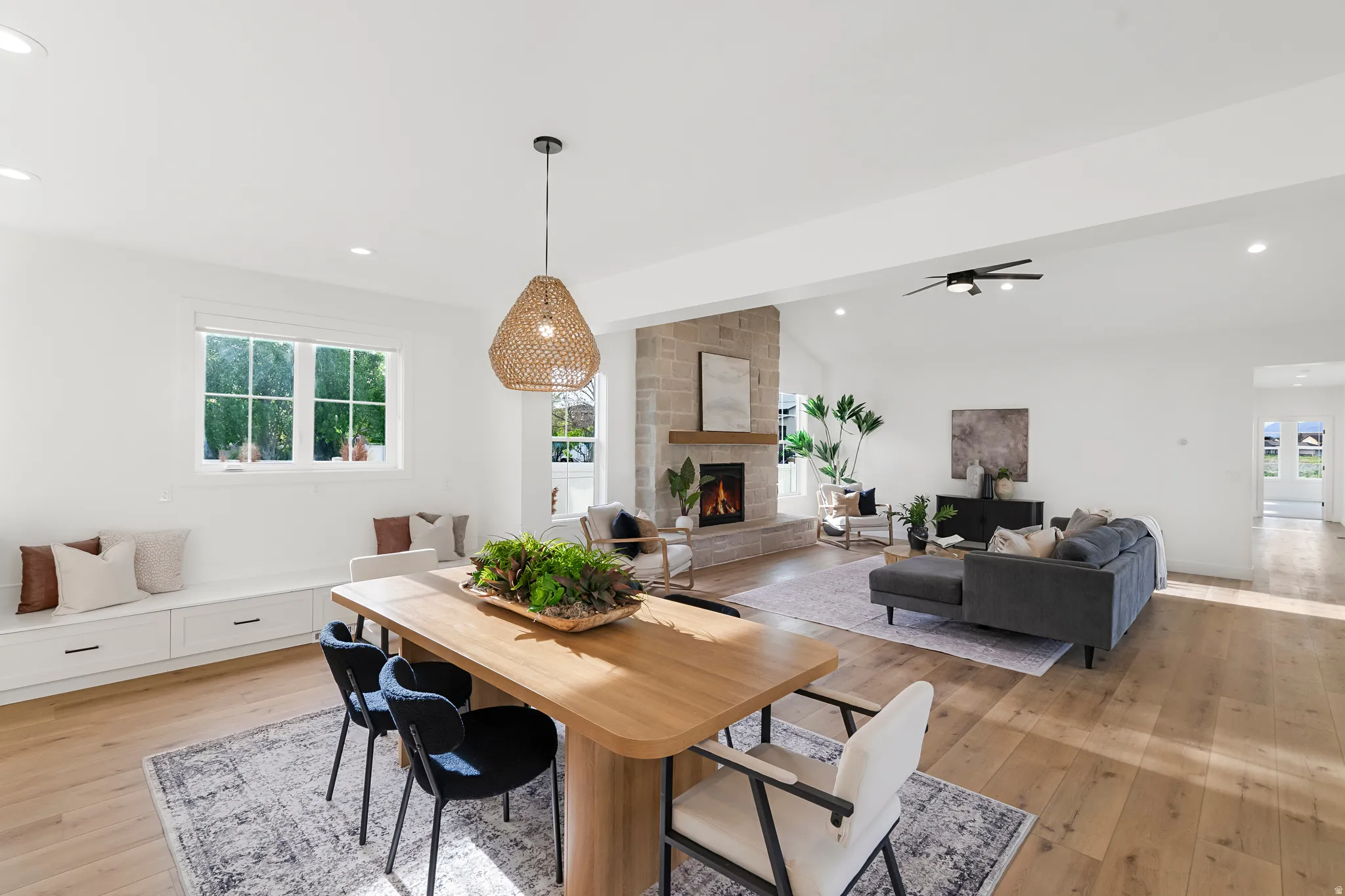 Dining room featuring lofted ceiling, light wood-type flooring, recessed lighting, a large fireplace, and a ceiling fan