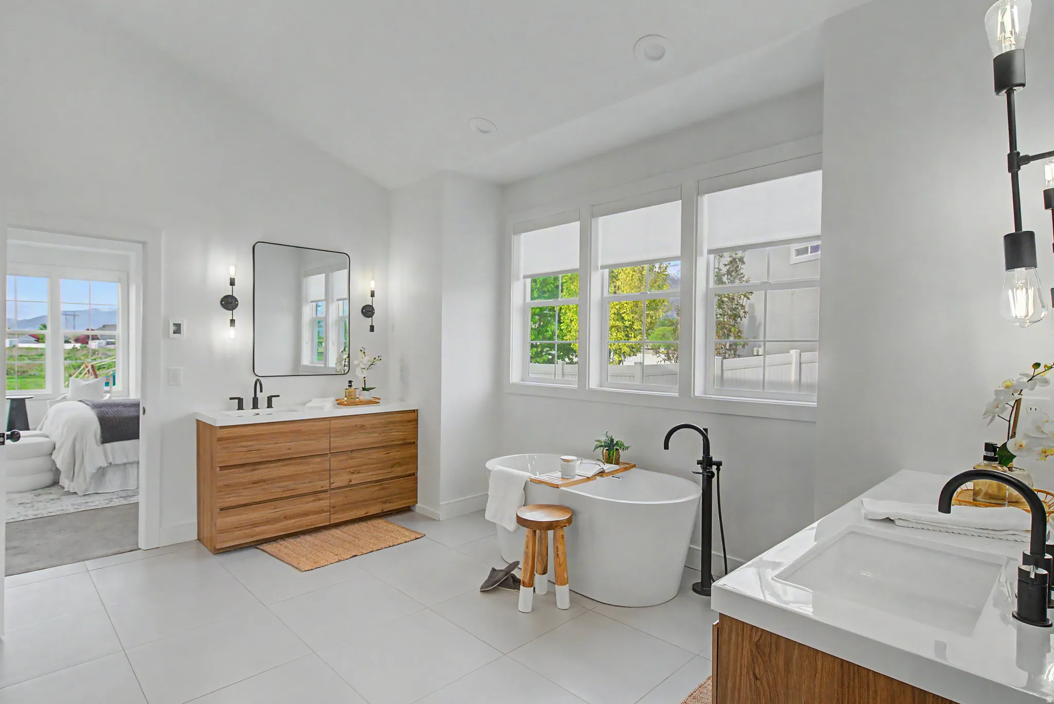 Ensuite bathroom featuring vanity, a freestanding bath, lofted ceiling, and light tile patterned floors