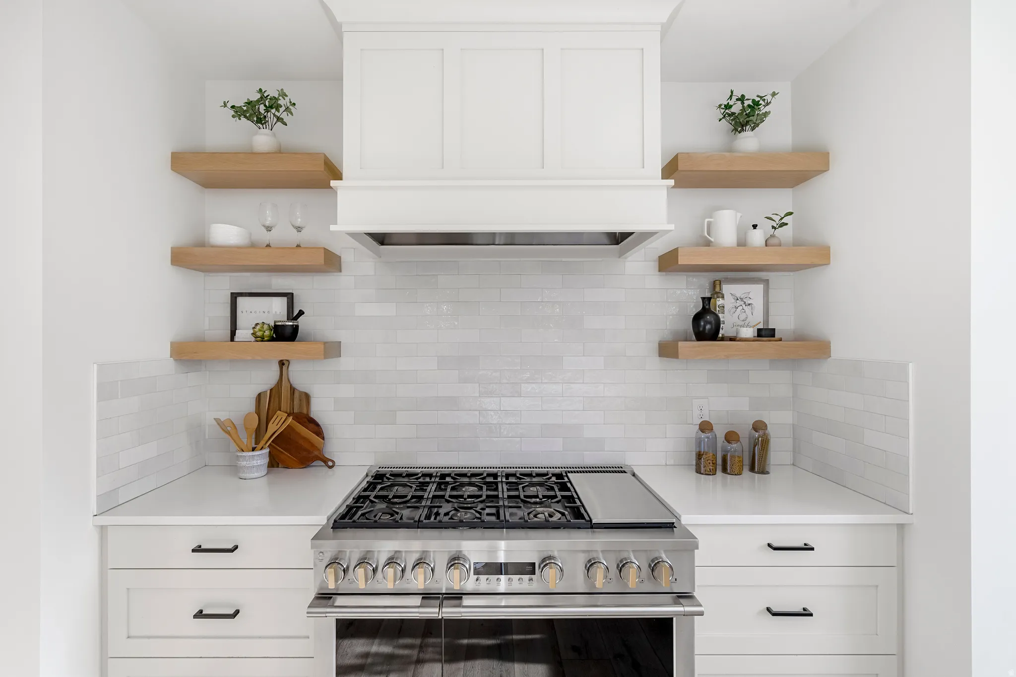 Kitchen with white cabinetry, open shelves, high end stainless steel range oven, and decorative backsplash