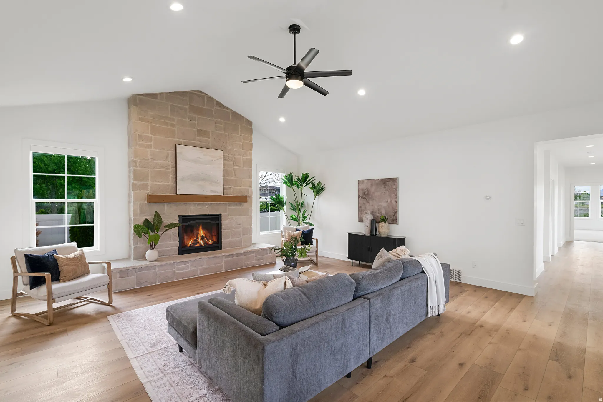 Living area featuring light wood-style floors, healthy amount of natural light, a ceiling fan, a fireplace, and recessed lighting