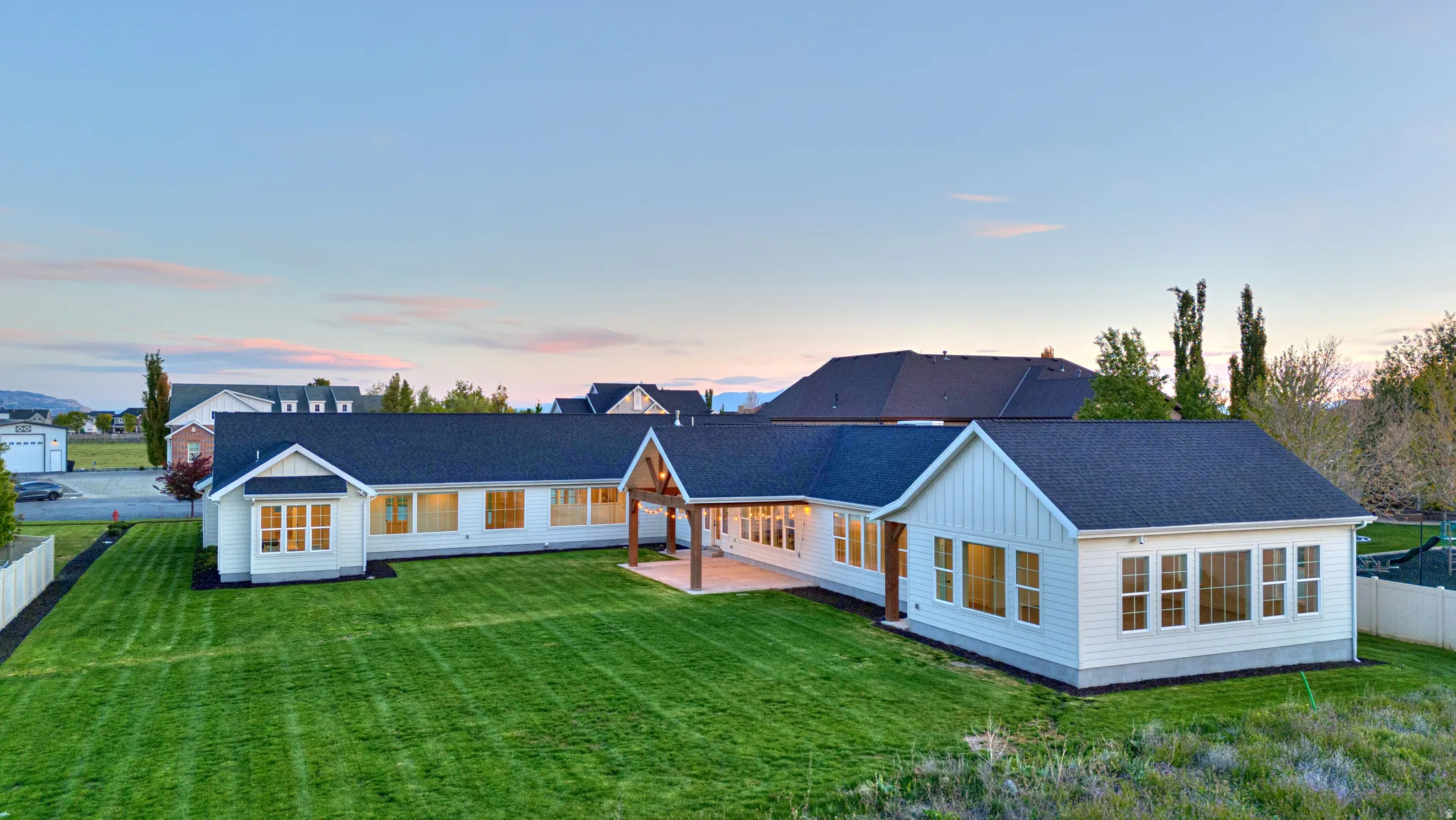 Rear view of property featuring roof with shingles, a patio area, and board and batten siding