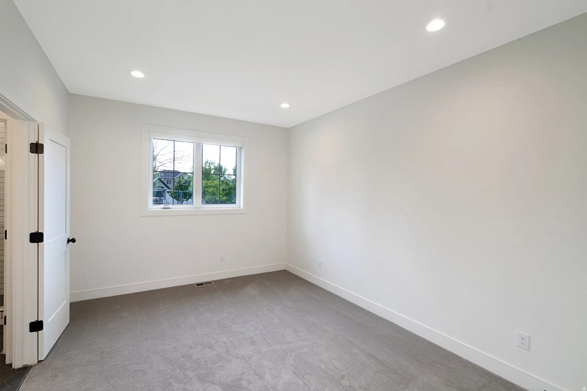 Empty room with light colored carpet and recessed lighting