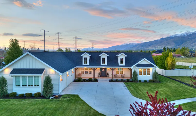 View of front facade featuring covered porch, roof with shingles, board and batten siding, driveway, and a mountain view