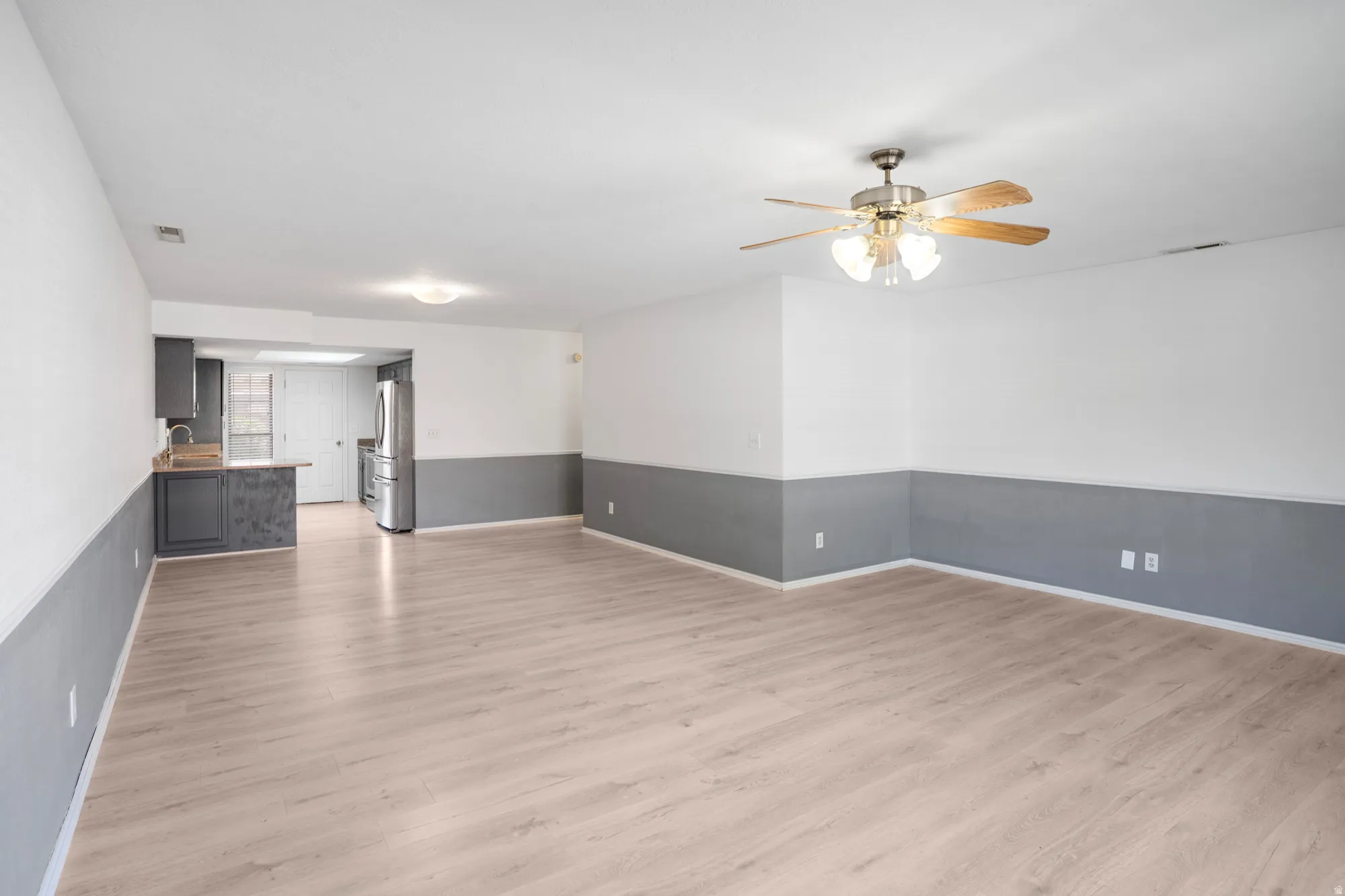 Unfurnished living room with light wood-type flooring and ceiling fan