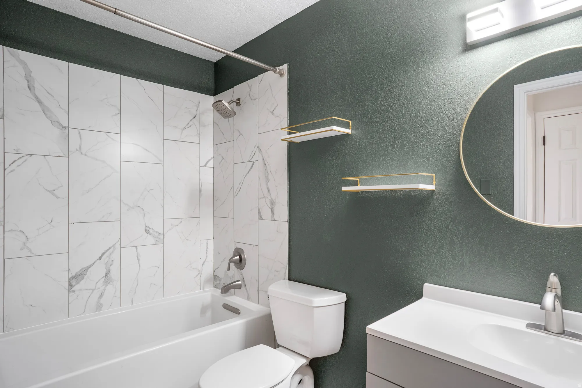 Bathroom with a textured wall, vanity, and bathing tub / shower combination