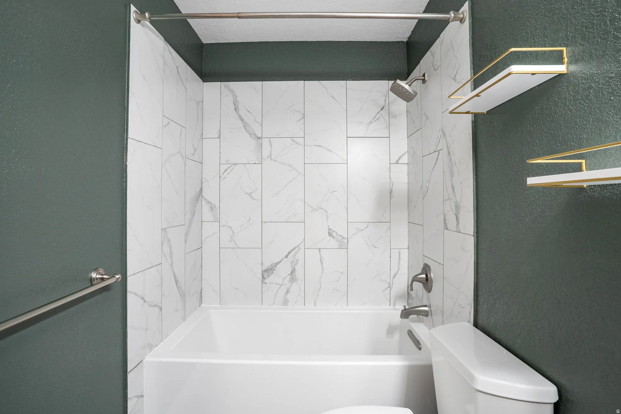 Bathroom featuring a textured wall and shower / washtub combination