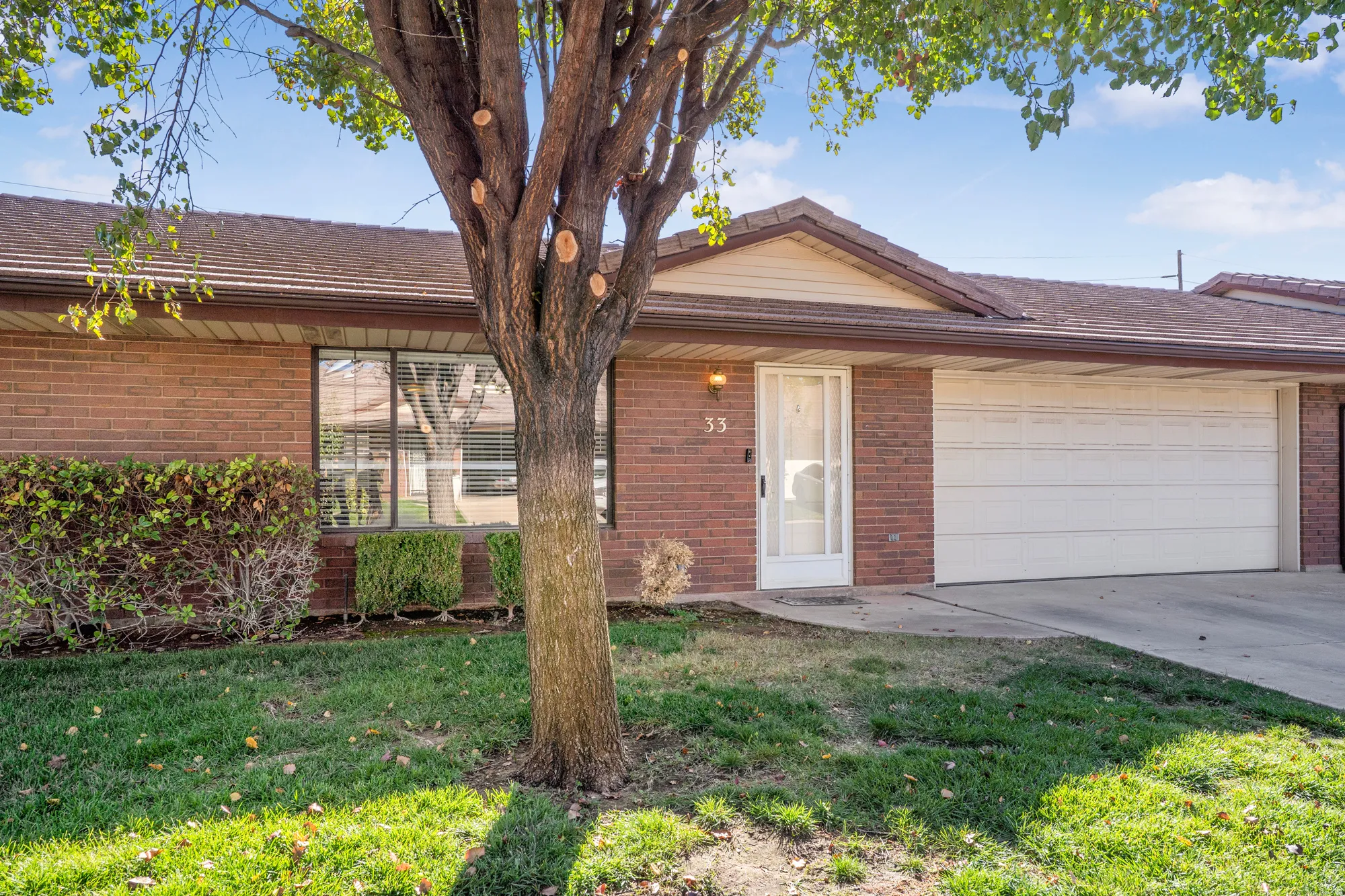 View of front of home featuring a front yard, a garage, driveway, and brick siding