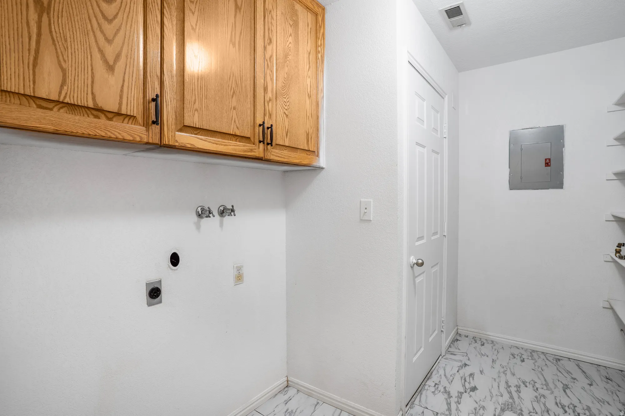 Laundry room with light marble finish floors, electric panel, cabinet space, washer hookup, and electric dryer hookup