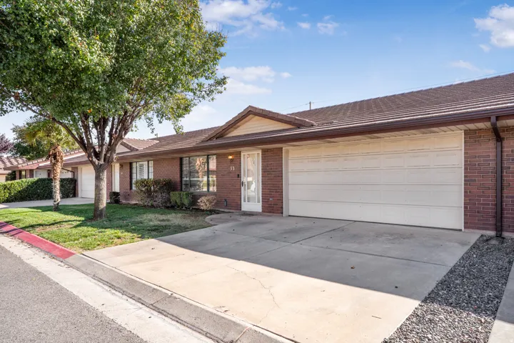 Single story home with driveway, a garage, a front yard, brick siding, and a tile roof