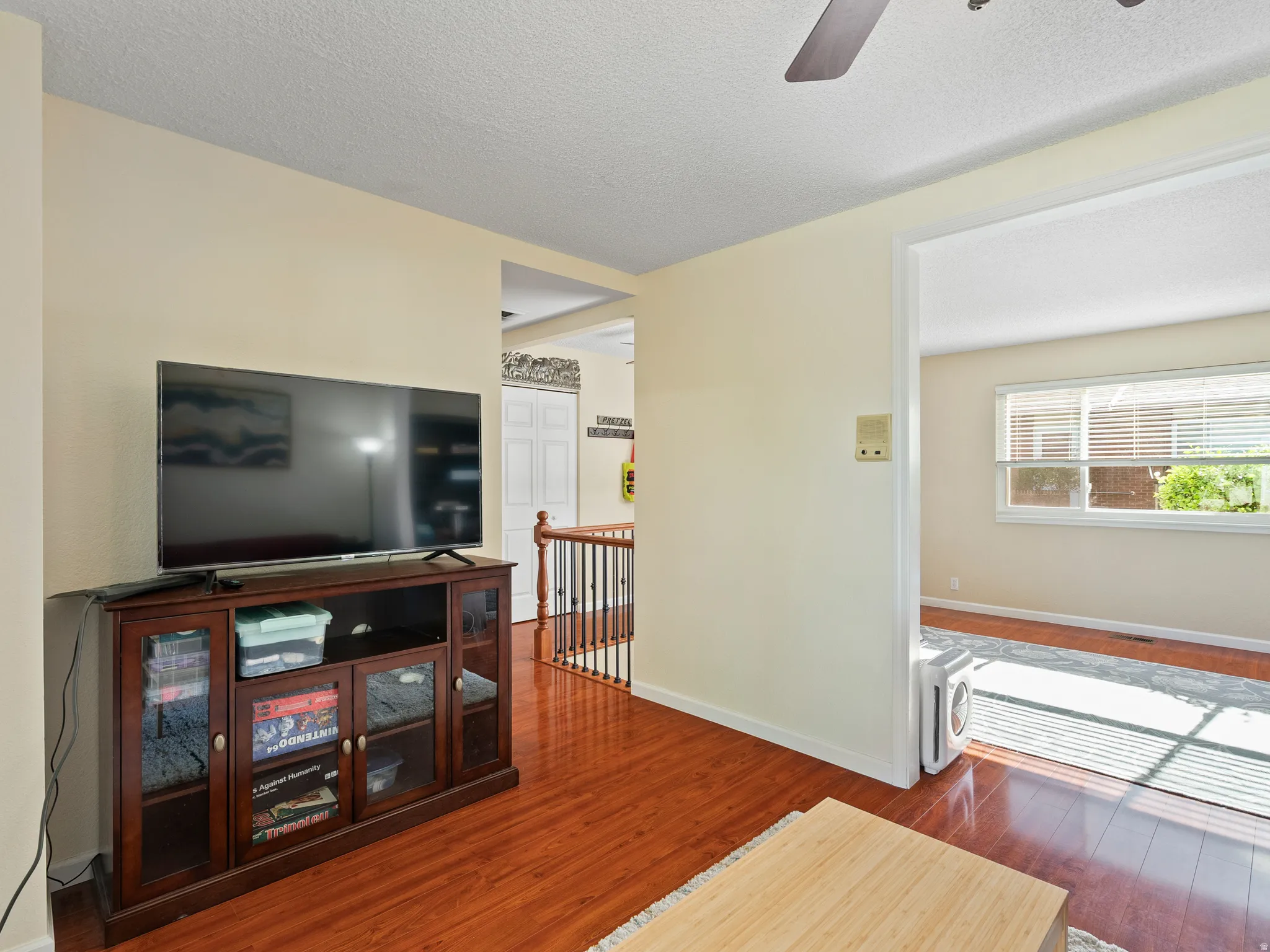 Living room with dark wood finished floors, a textured ceiling, and a ceiling fan