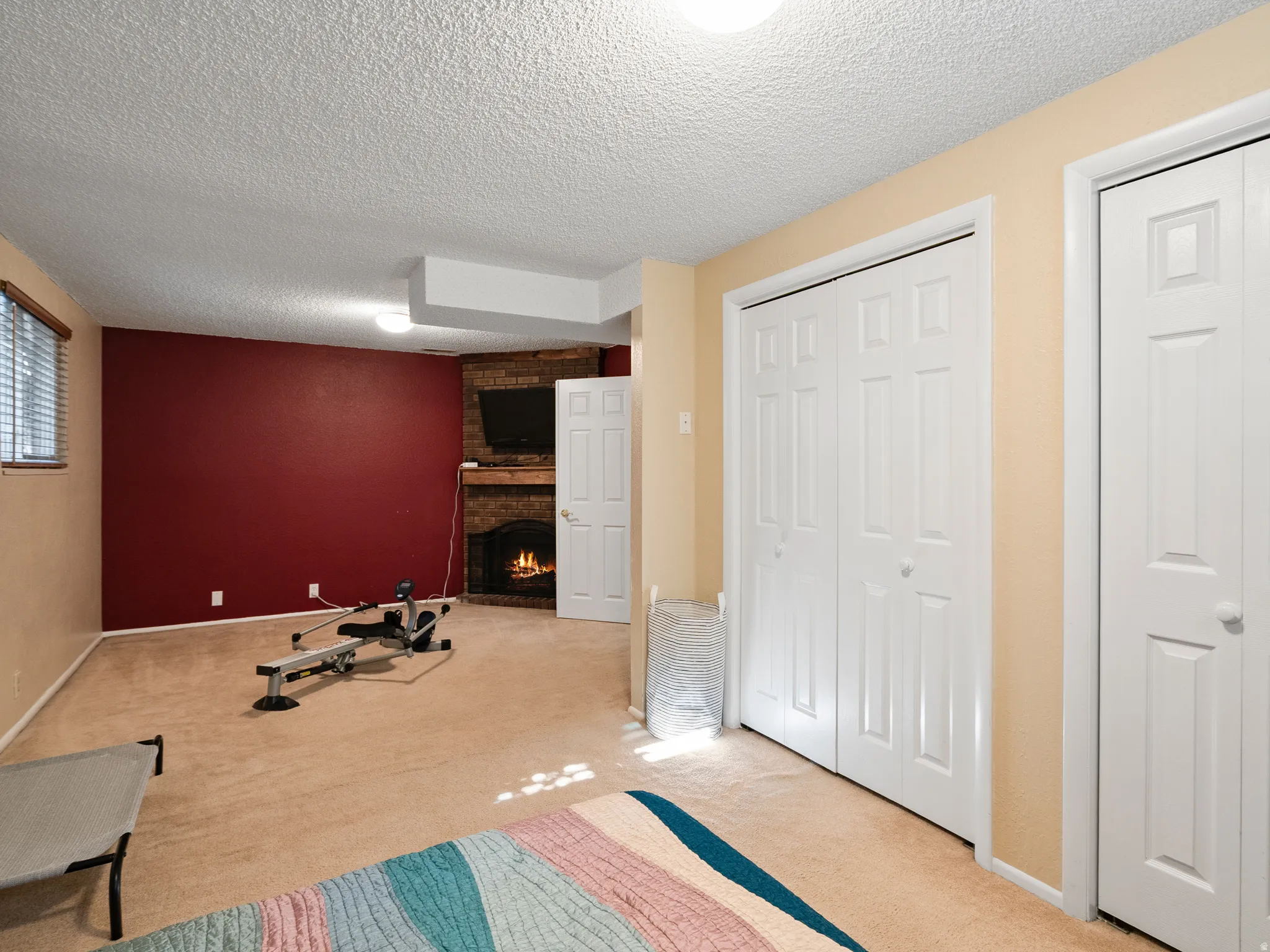 Unfurnished bedroom featuring multiple closets, a fireplace, light carpet, and a textured ceiling