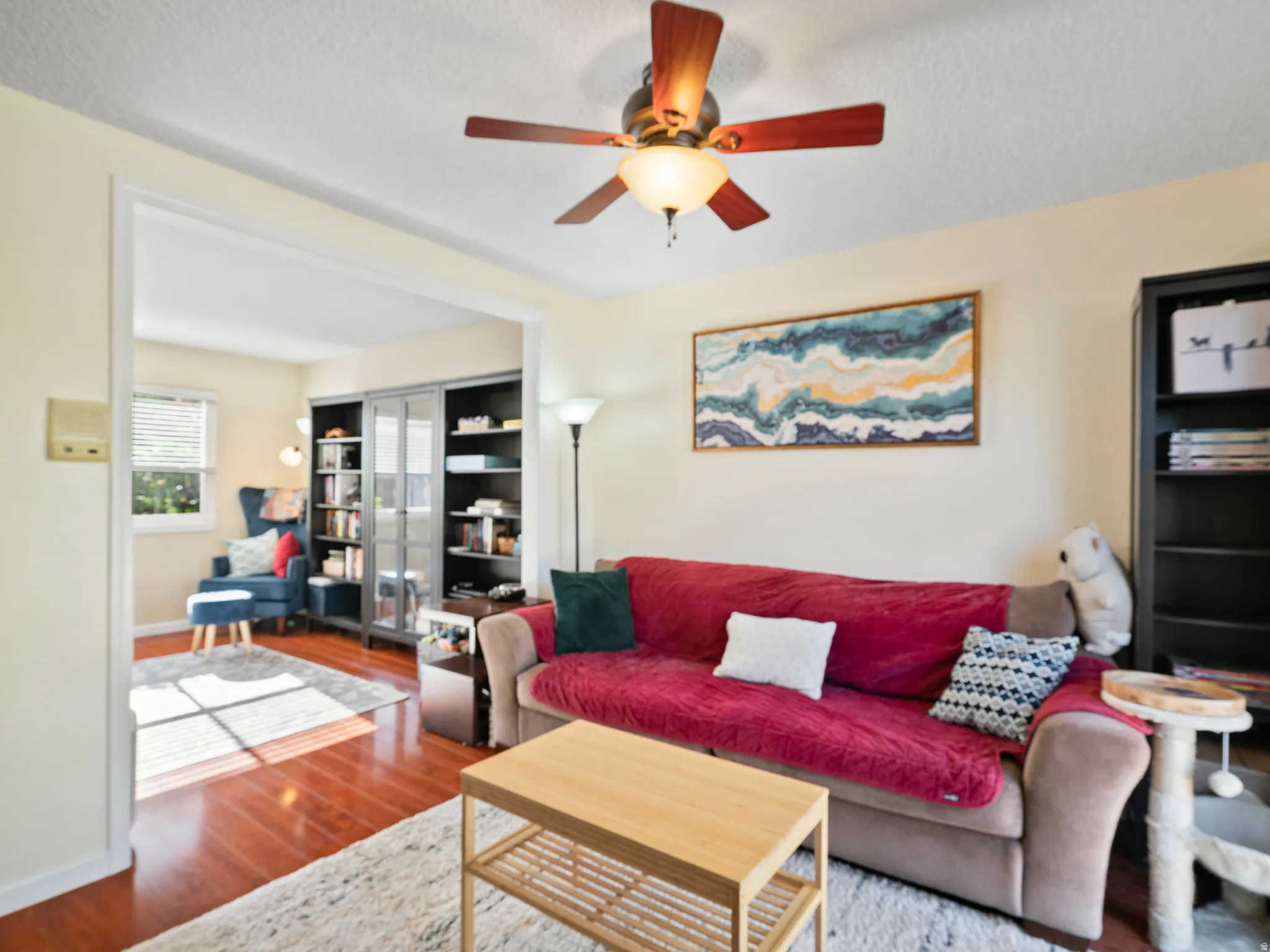 Living area featuring wood finished floors, a ceiling fan, and a textured ceiling