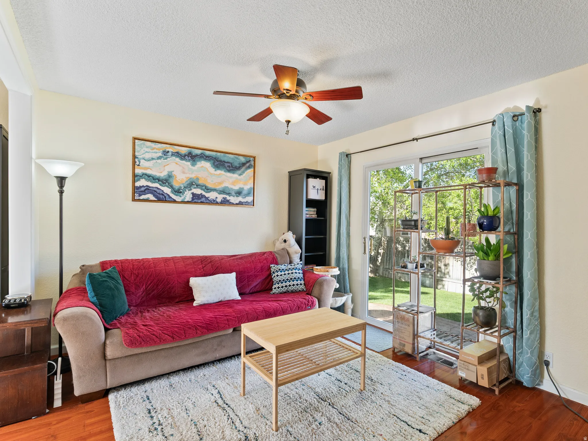 Living room featuring wood finished floors, ceiling fan, and a textured ceiling