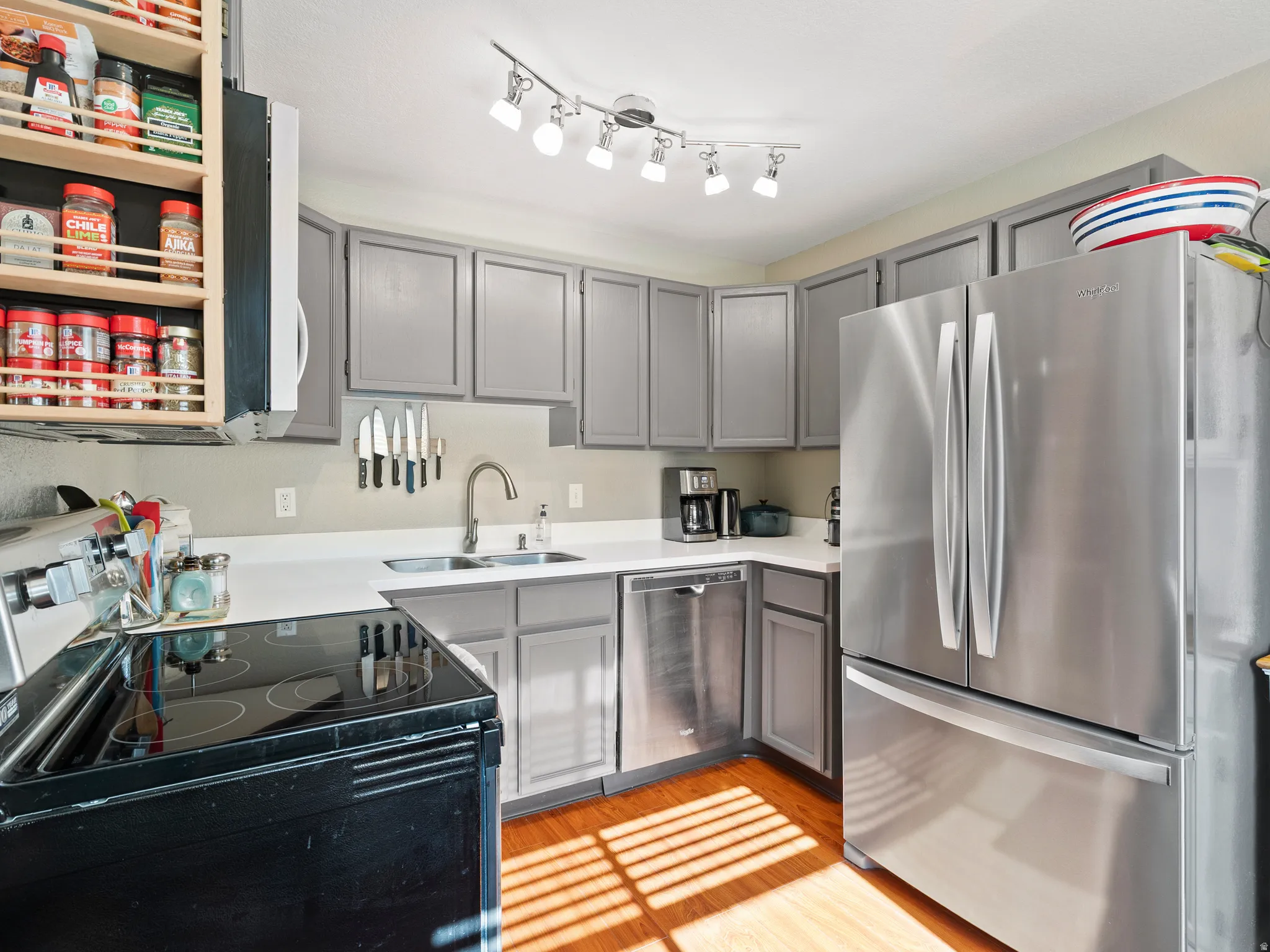 Kitchen with stainless steel appliances, light countertops, gray cabinets, and light wood-style floors
