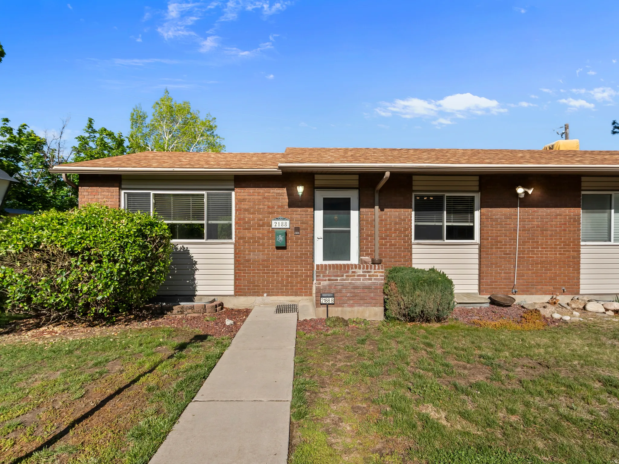 Single story home featuring a front yard, roof with shingles, and brick siding