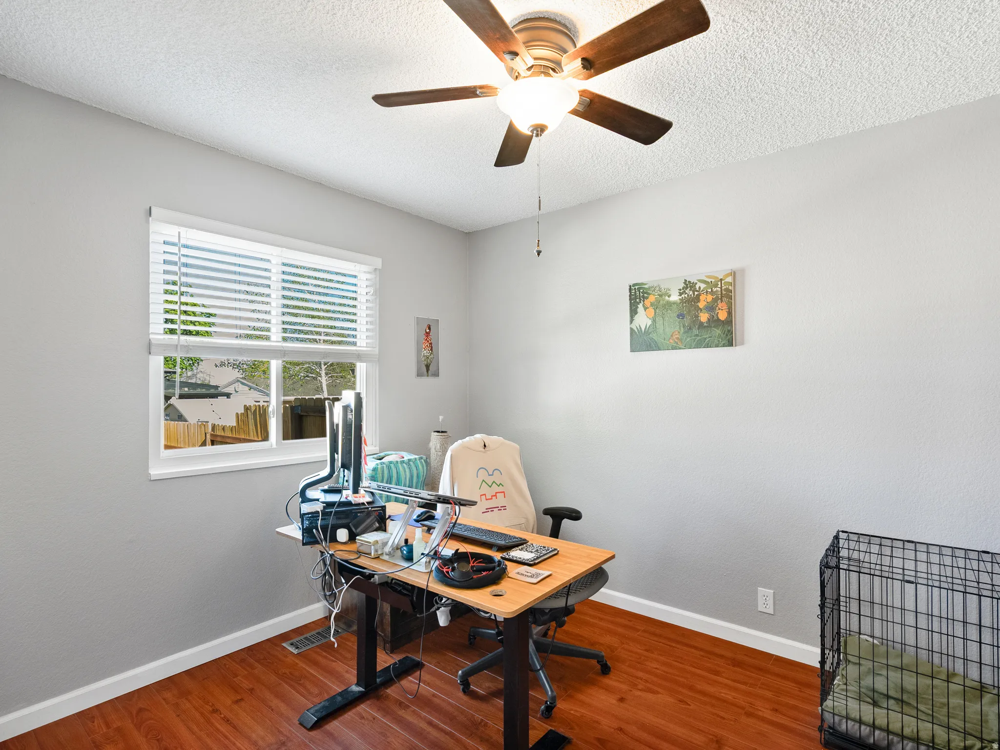 Home office with a ceiling fan, wood finished floors, and a textured ceiling