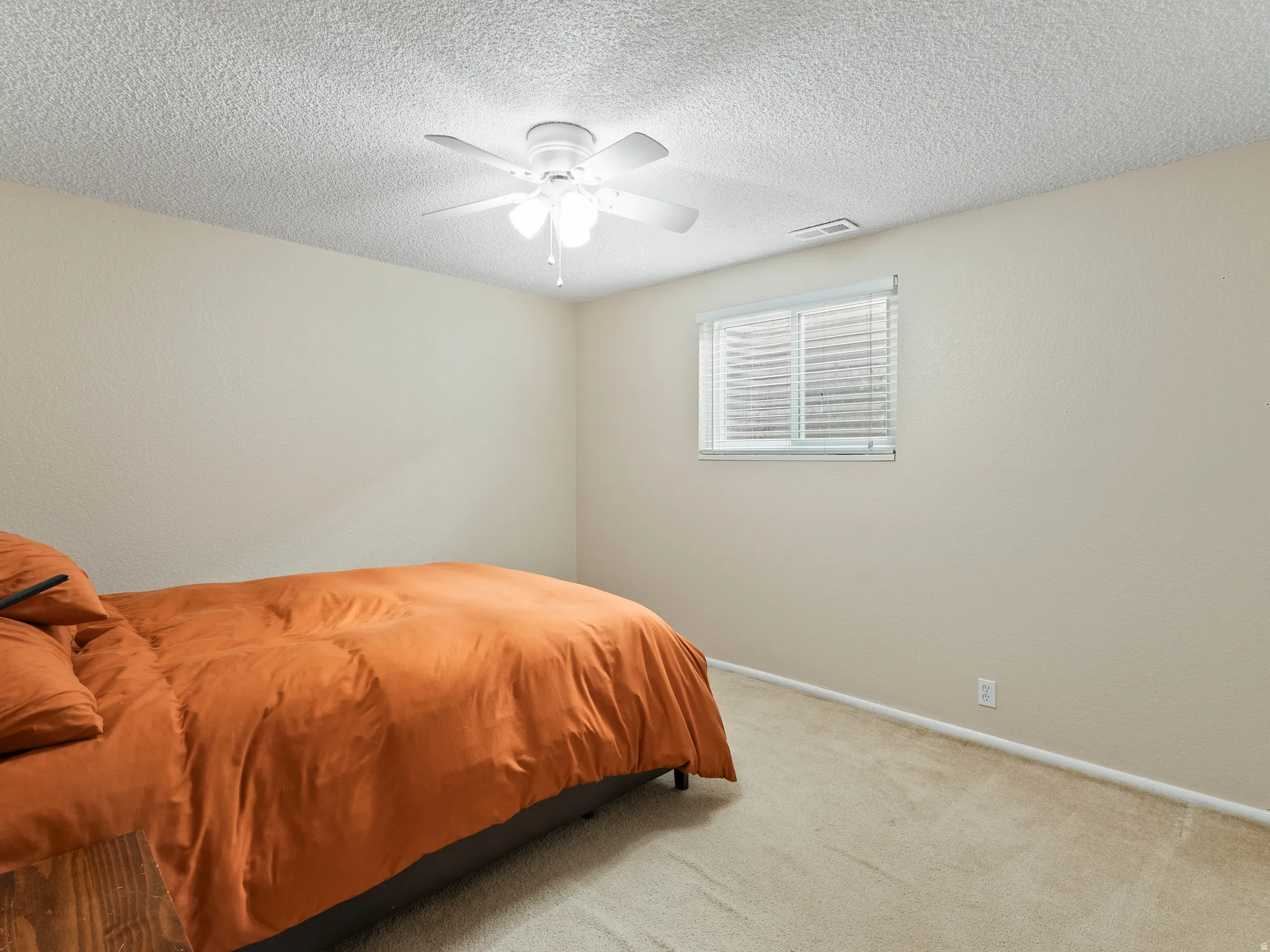 Bedroom featuring light colored carpet, a ceiling fan, and a textured ceiling