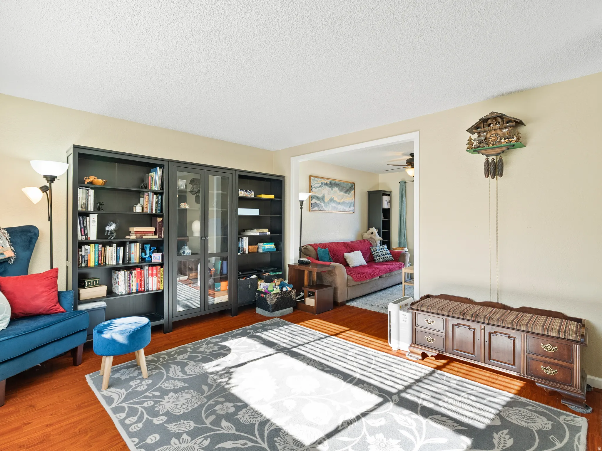 Living area with dark wood finished floors, a ceiling fan, and a textured ceiling