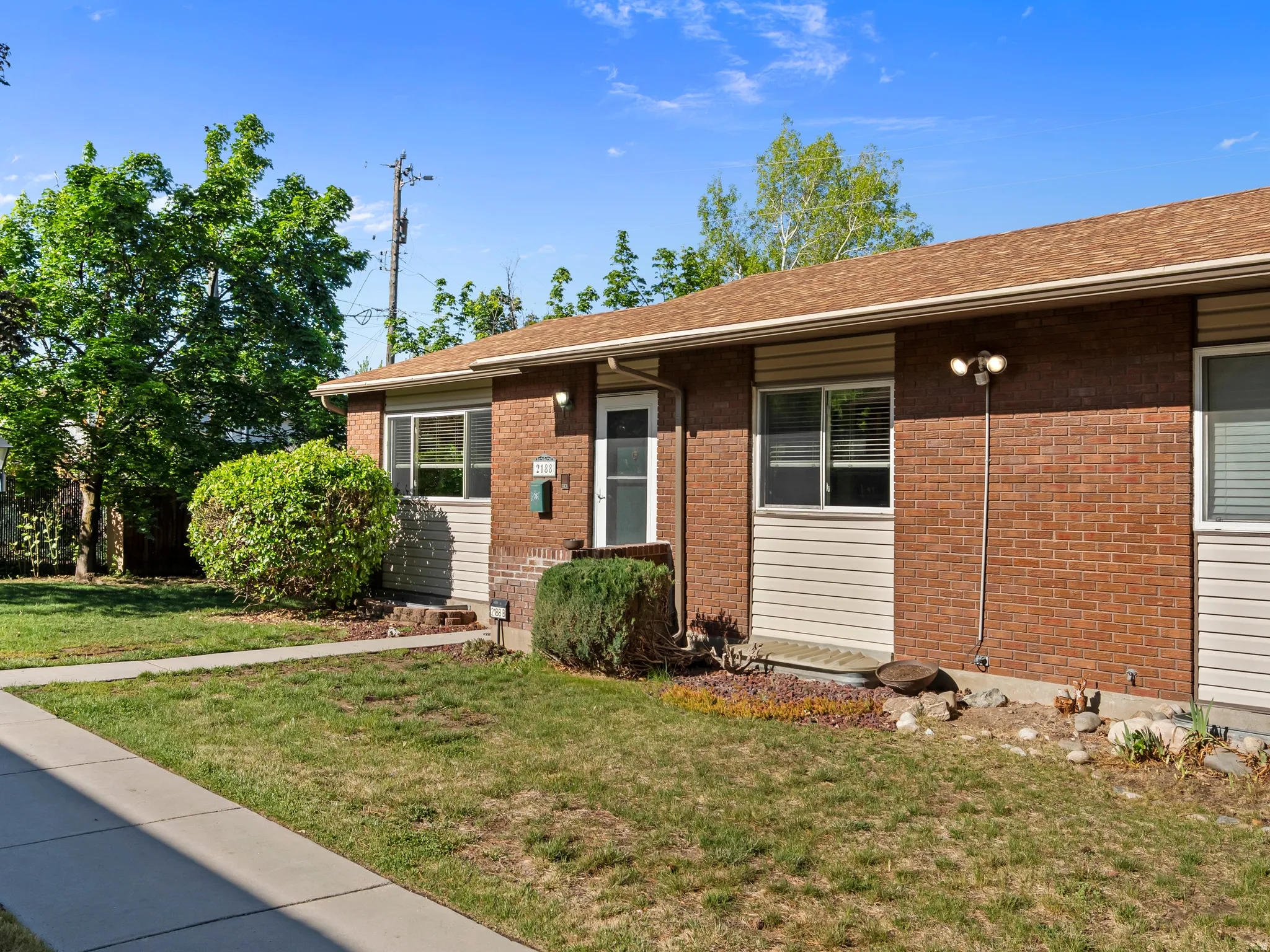View of front of home with a front lawn, brick siding, and roof with shingles