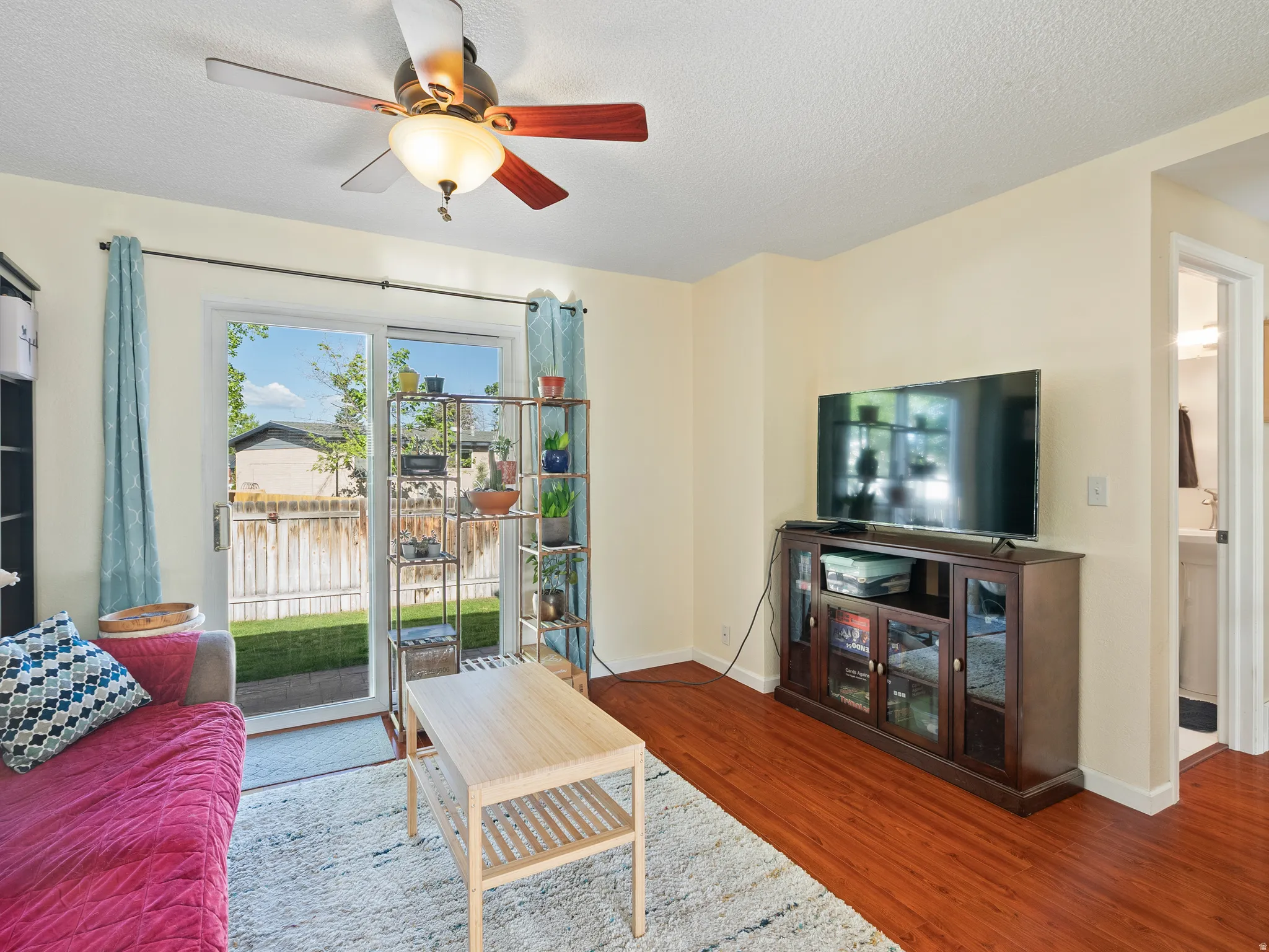 Living area featuring a ceiling fan, wood finished floors, and a textured ceiling