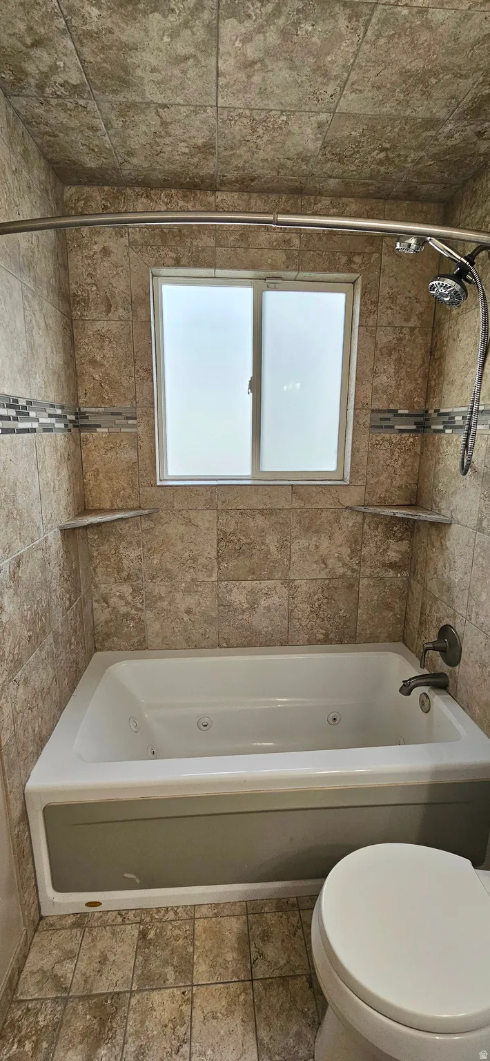 Full bath with a combined bath / shower with jetted tub and healthy amount of natural light