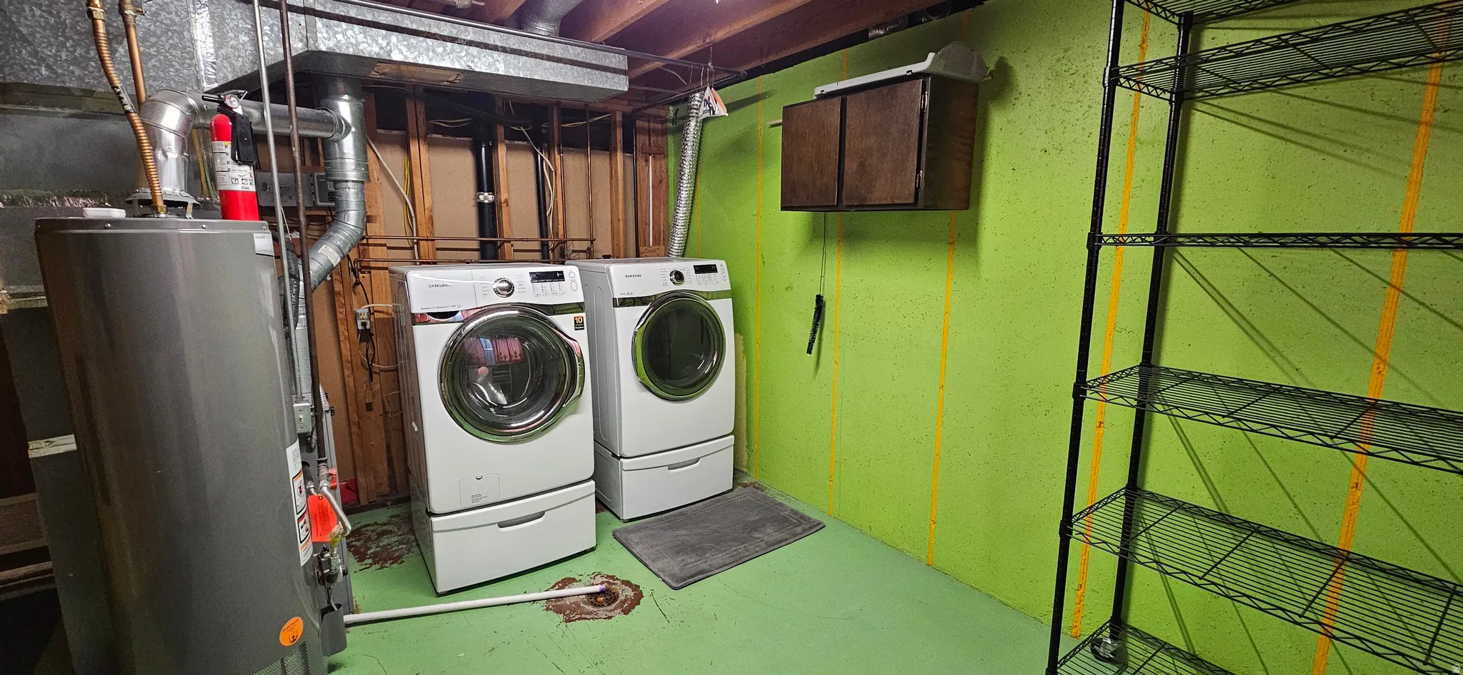 Laundry area with water heater, finished concrete flooring, cabinet space, and washing machine and clothes dryer
