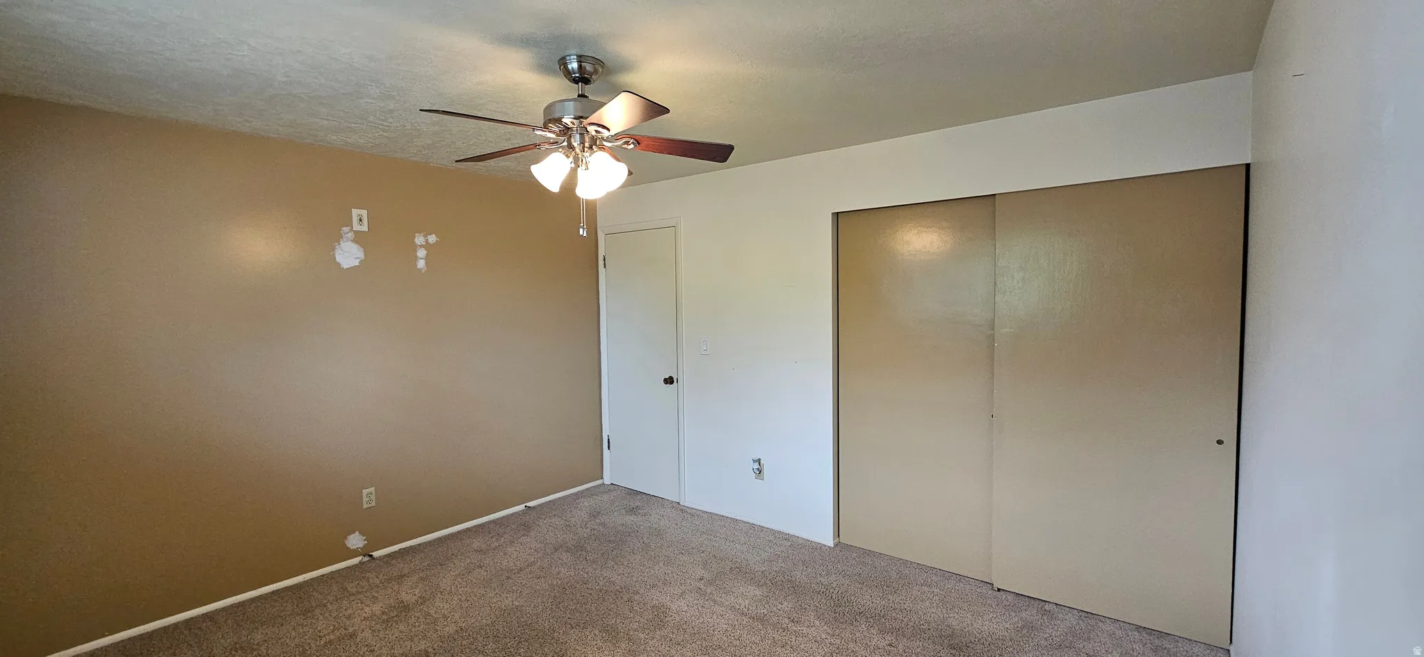 Unfurnished bedroom featuring carpet floors, a closet, ceiling fan, and a textured ceiling