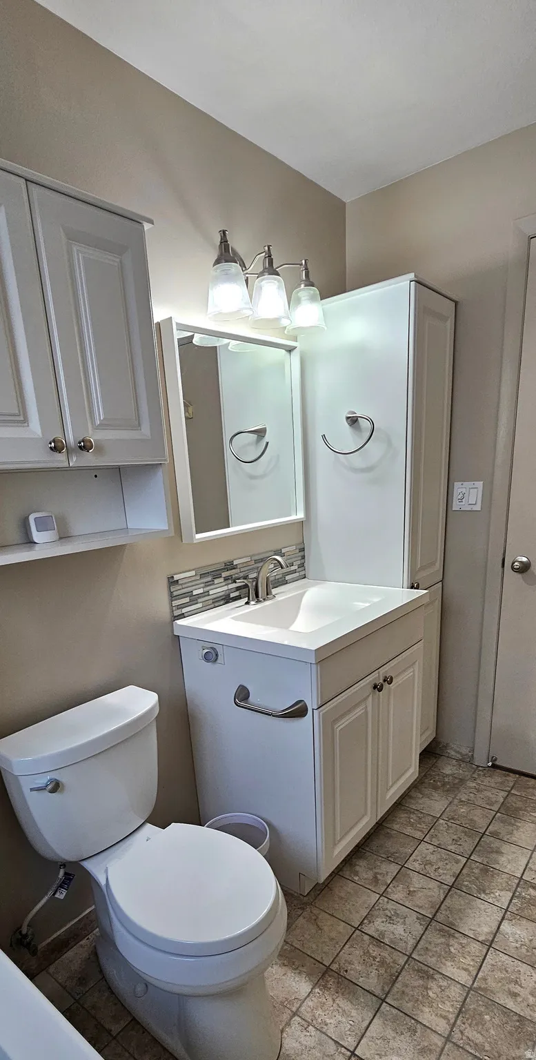 Half bath with vanity and light stone finish floors