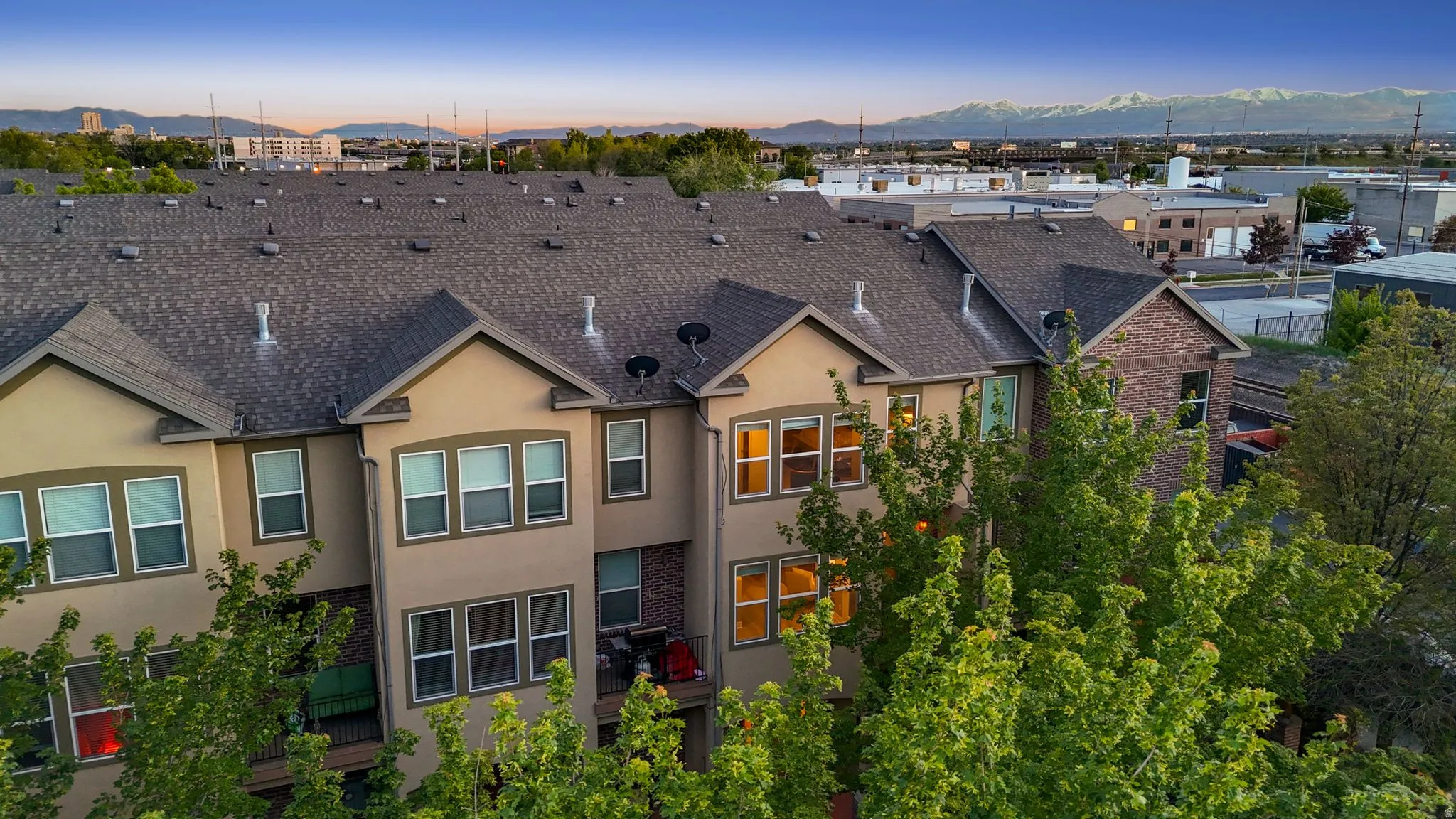 Back of house at dusk with a mountain view, stucco siding, and a shingled roof