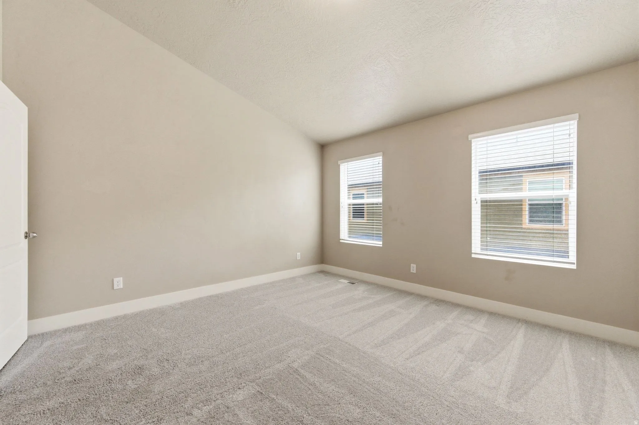 Empty room featuring light colored carpet and baseboards