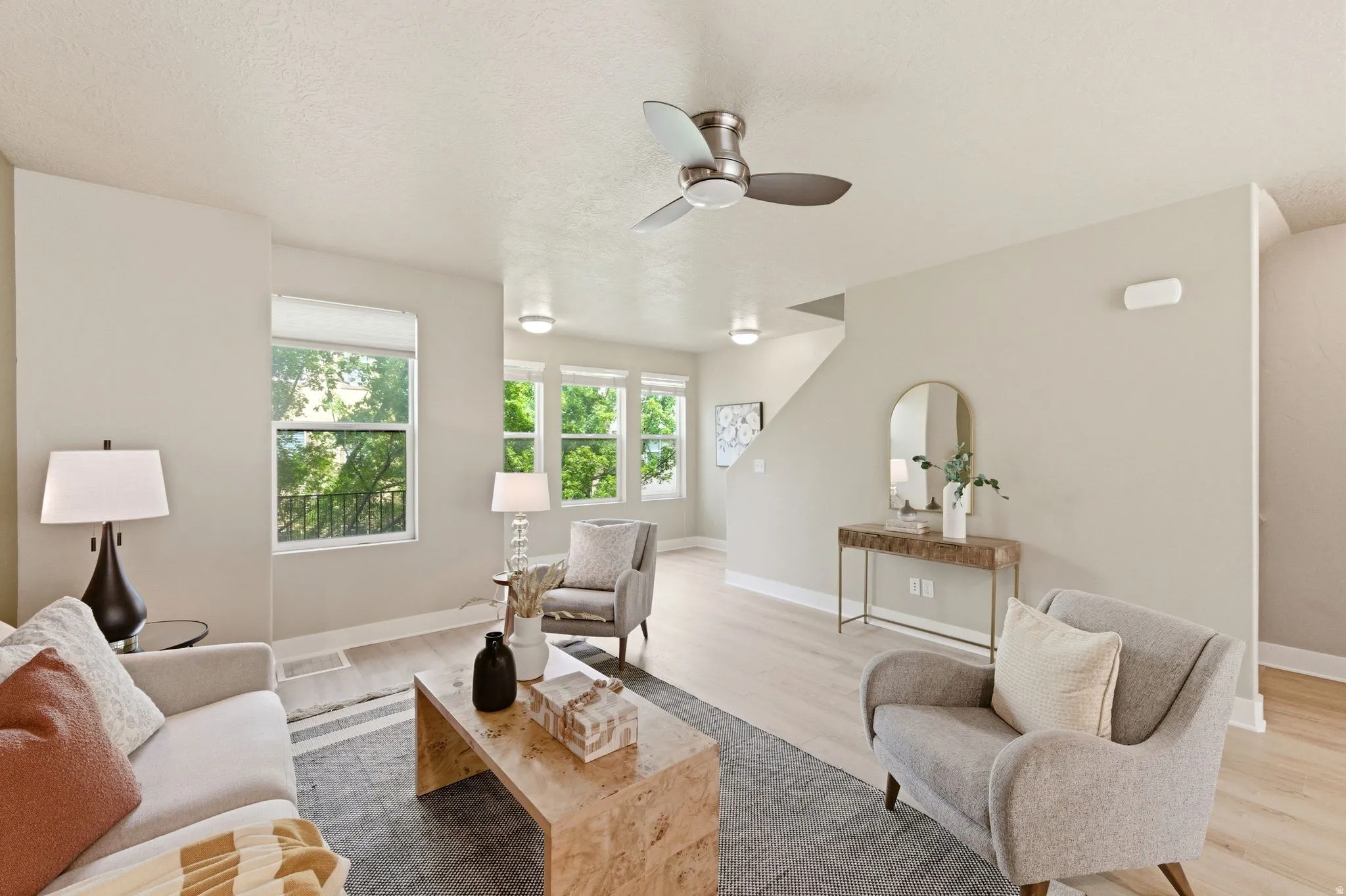 Living area with light wood-type flooring, ceiling fan, and a textured ceiling