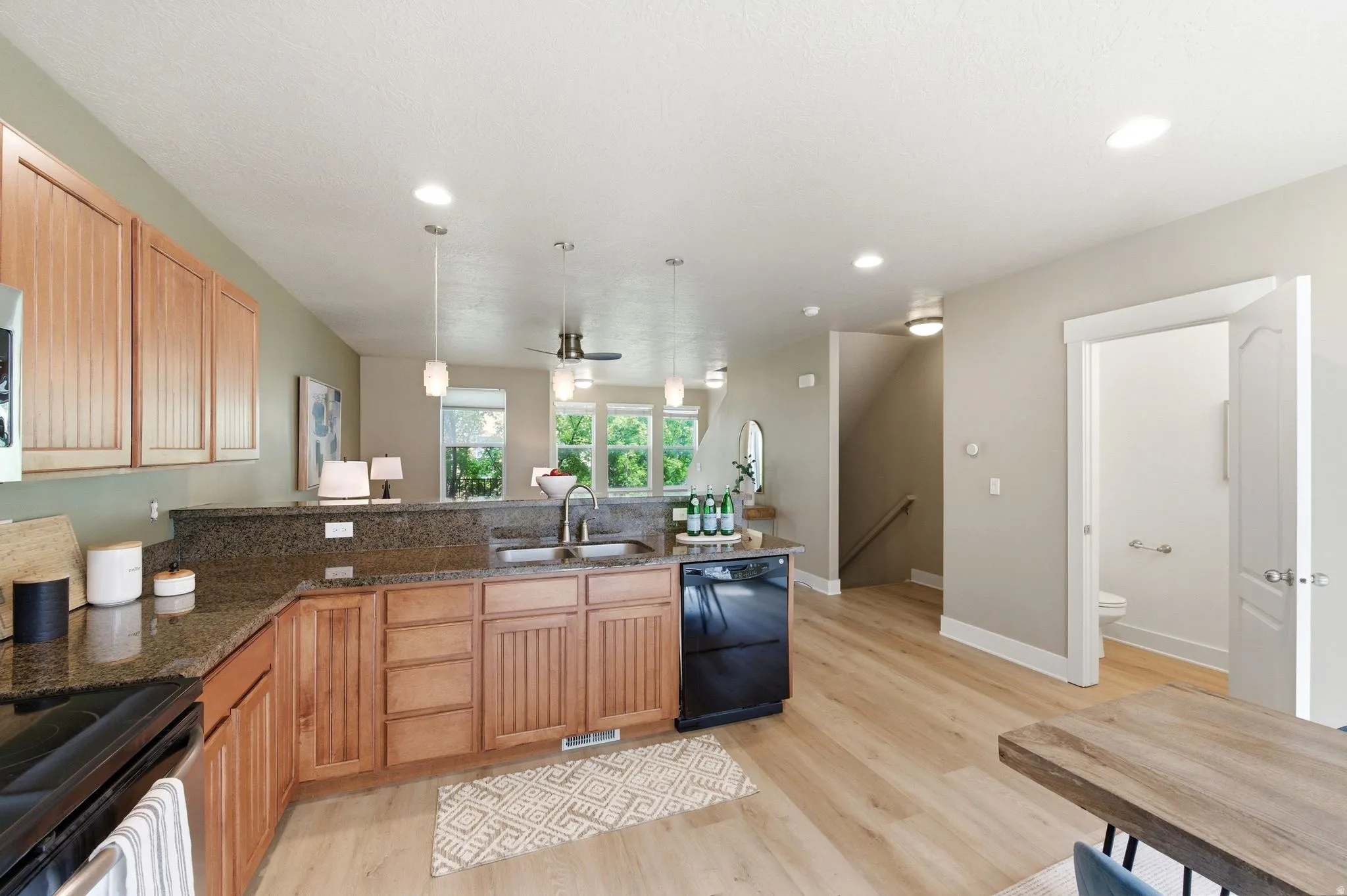 Kitchen with a peninsula, dark stone countertops, a ceiling fan, and light wood finished floors