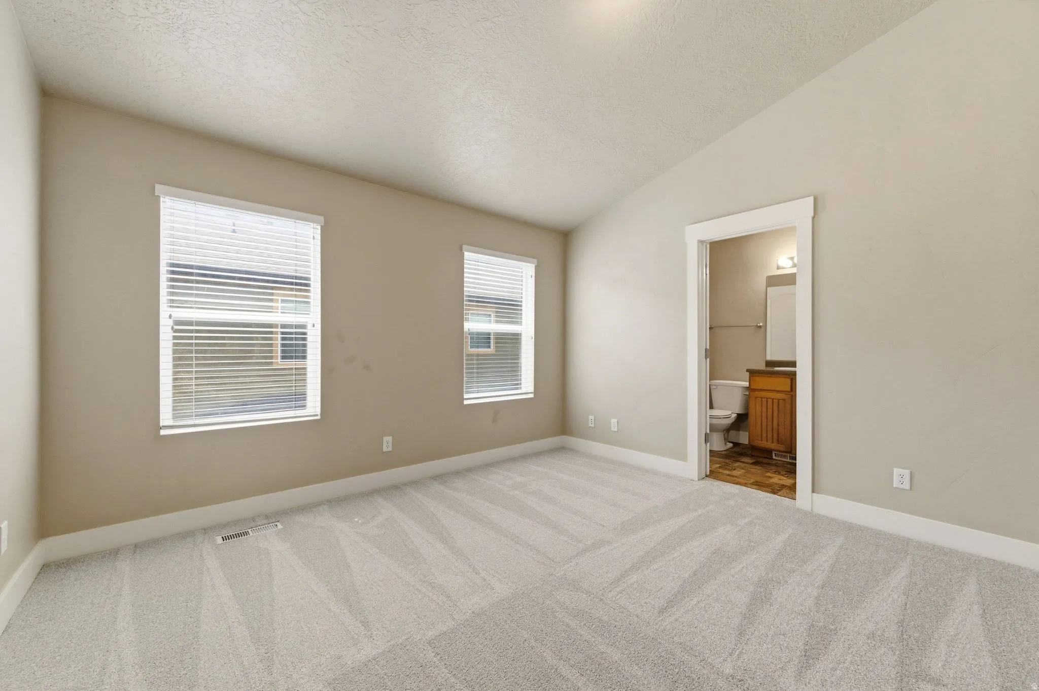 Unfurnished bedroom featuring light colored carpet and ensuite bath