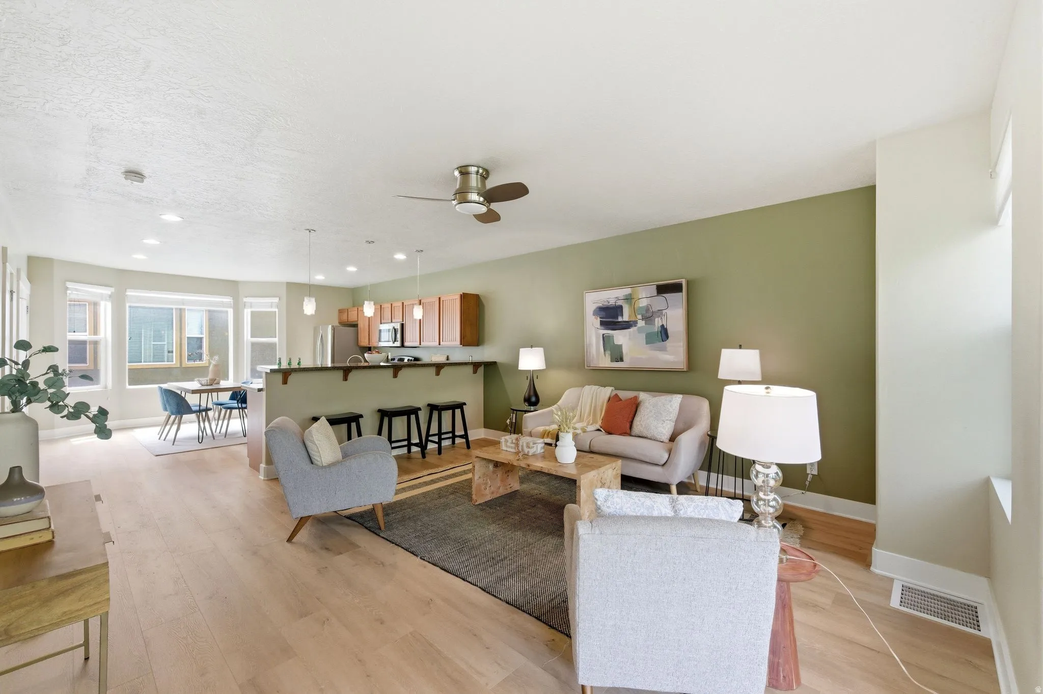 Living area with light wood-style floors, a ceiling fan, and recessed lighting