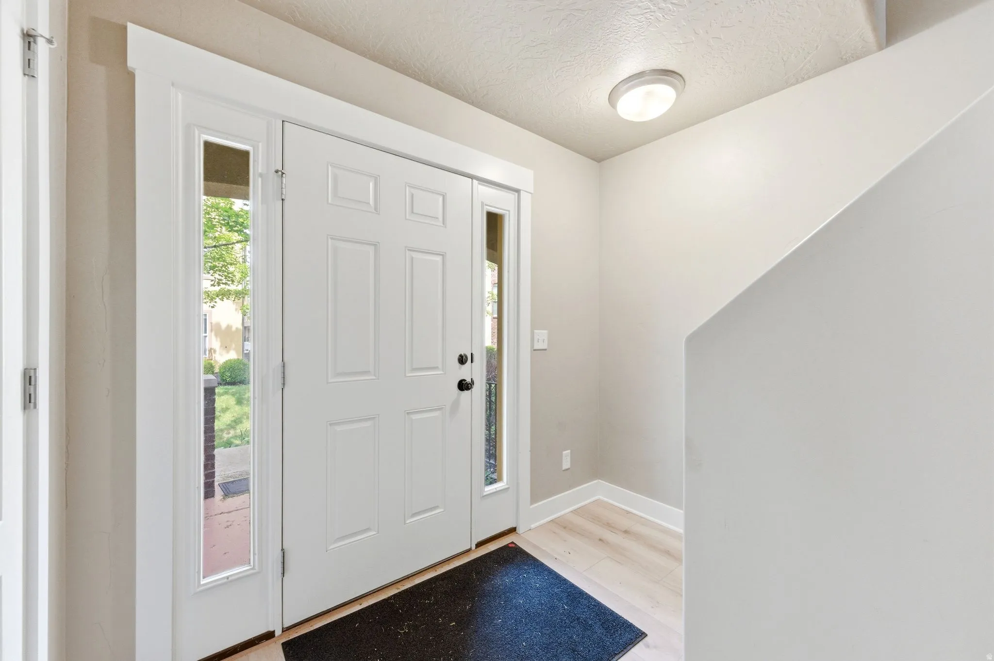 Foyer featuring light wood-style flooring and a textured ceiling