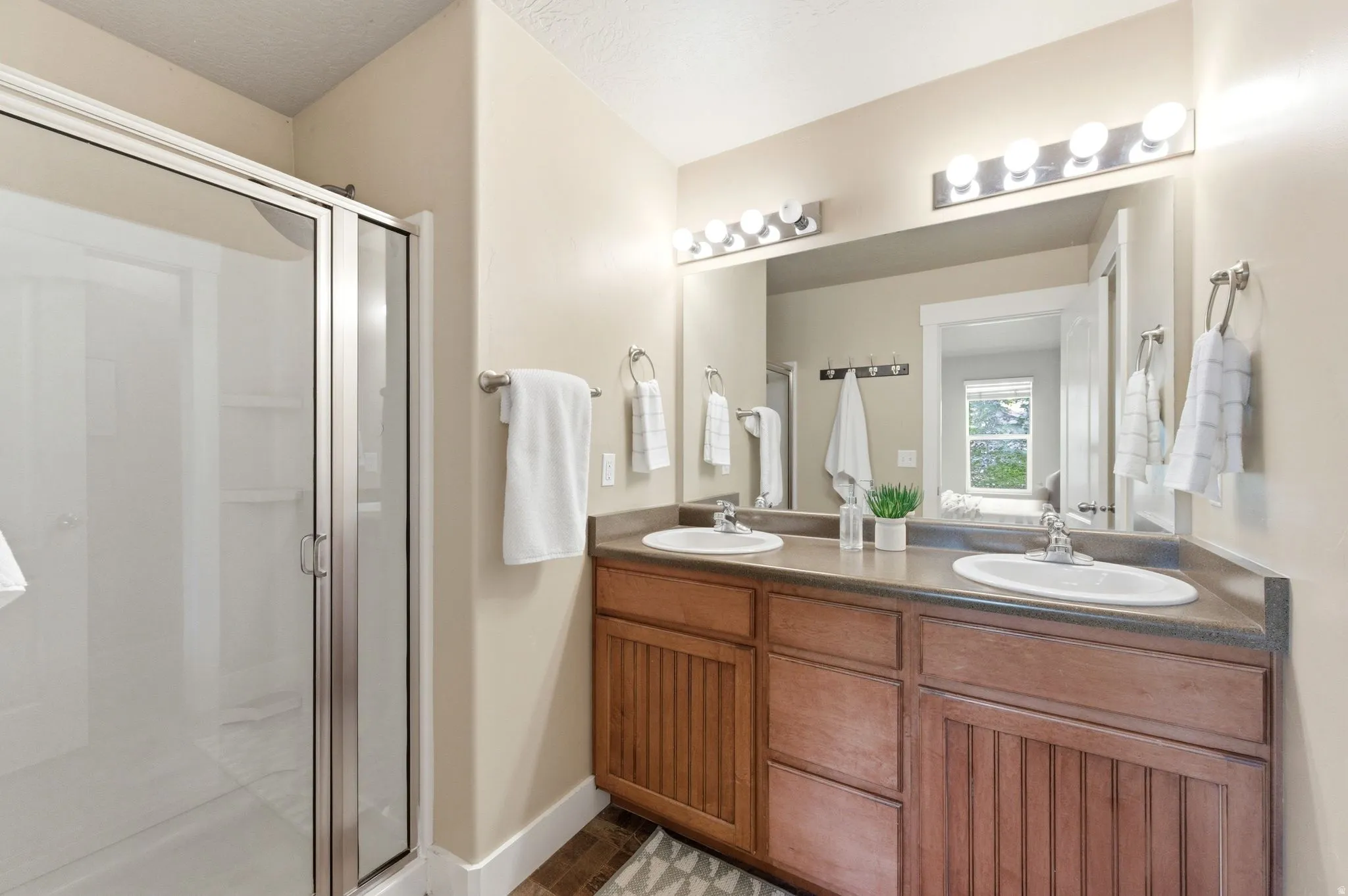 Full bath with double vanity and a stall shower
