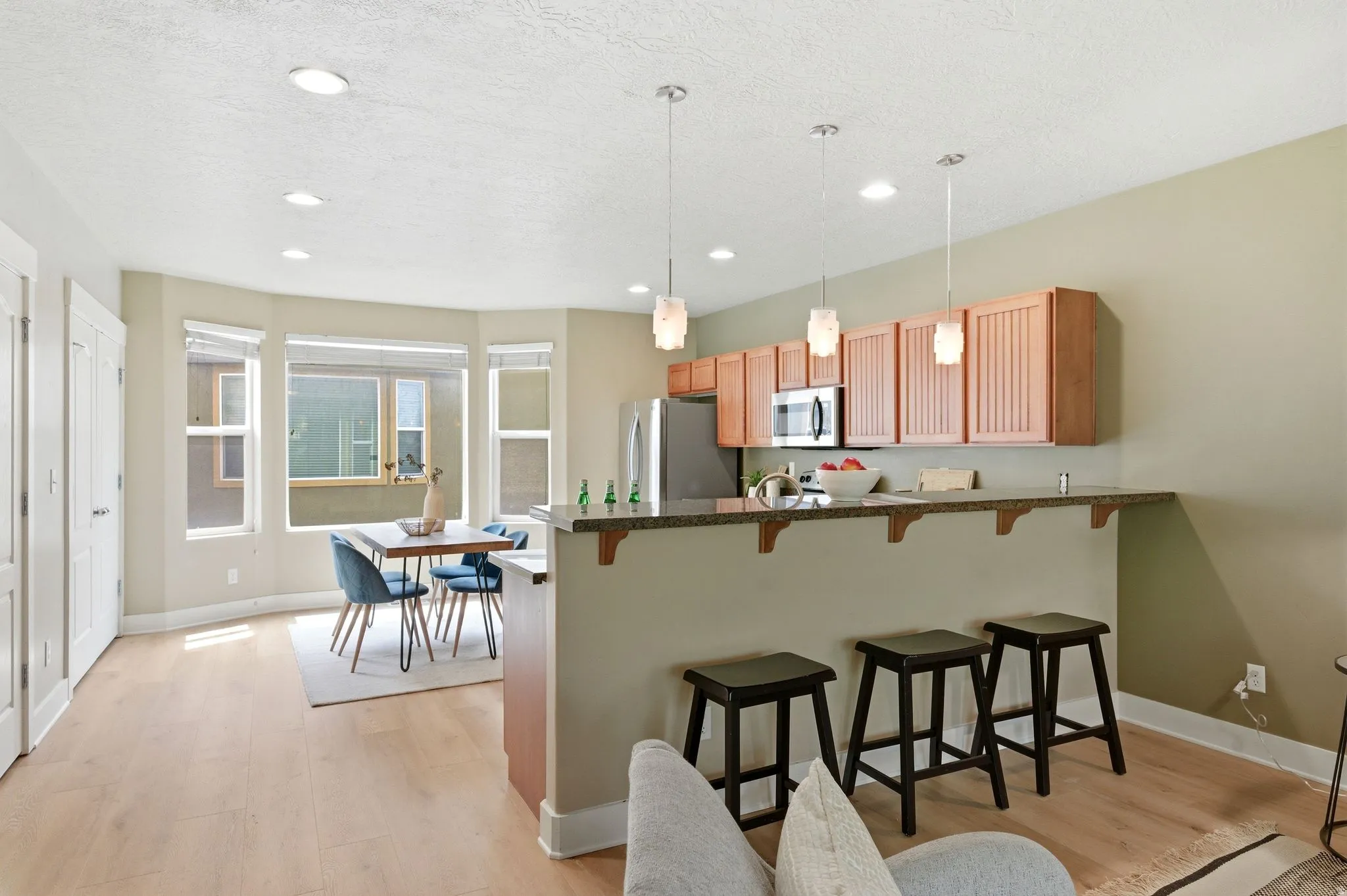 Kitchen with a kitchen breakfast bar, a peninsula, light wood-type flooring, decorative light fixtures, and stainless steel appliances