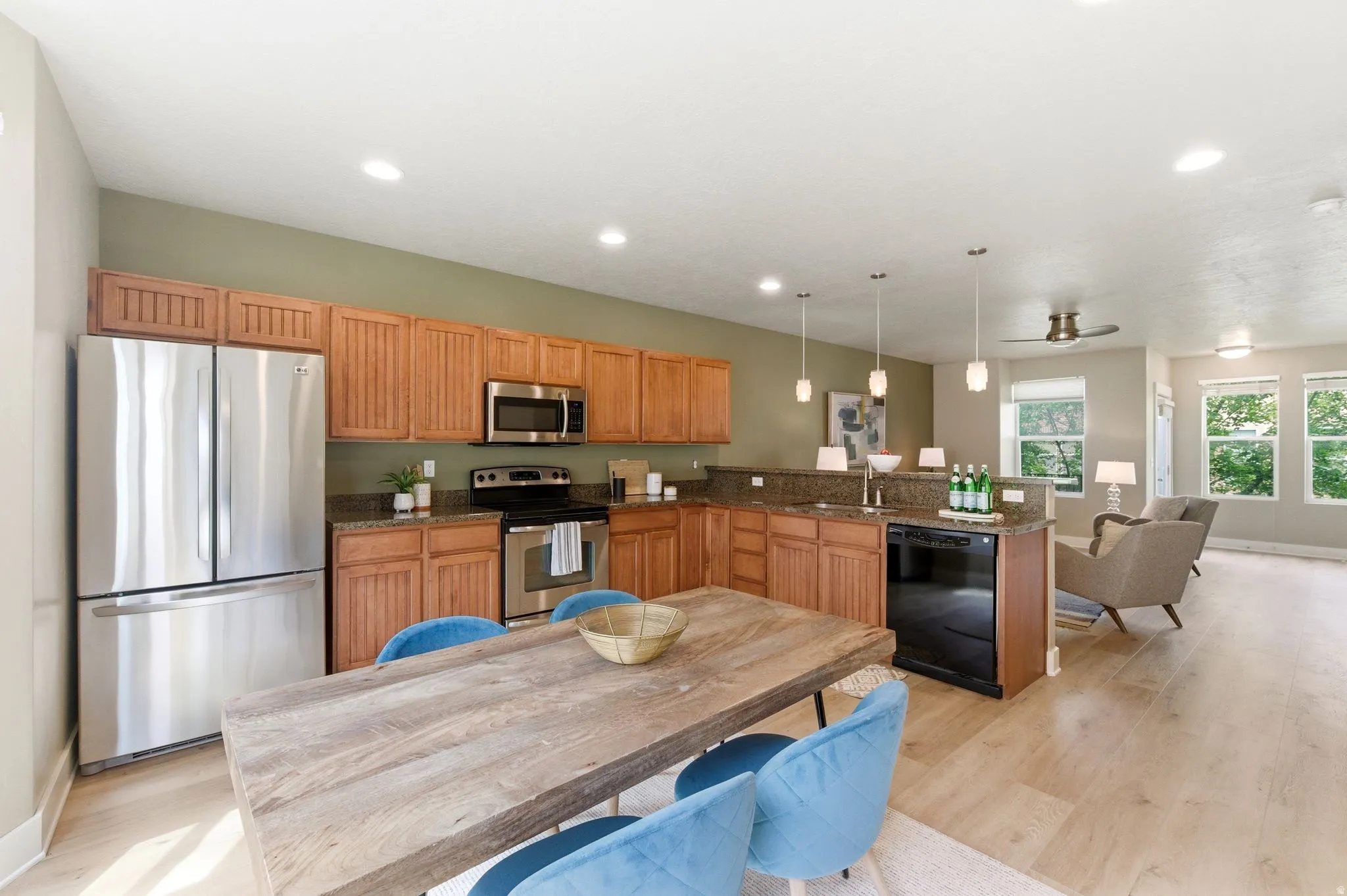 Kitchen featuring stainless steel appliances, dark stone countertops, a peninsula, light wood finished floors, and pendant lighting