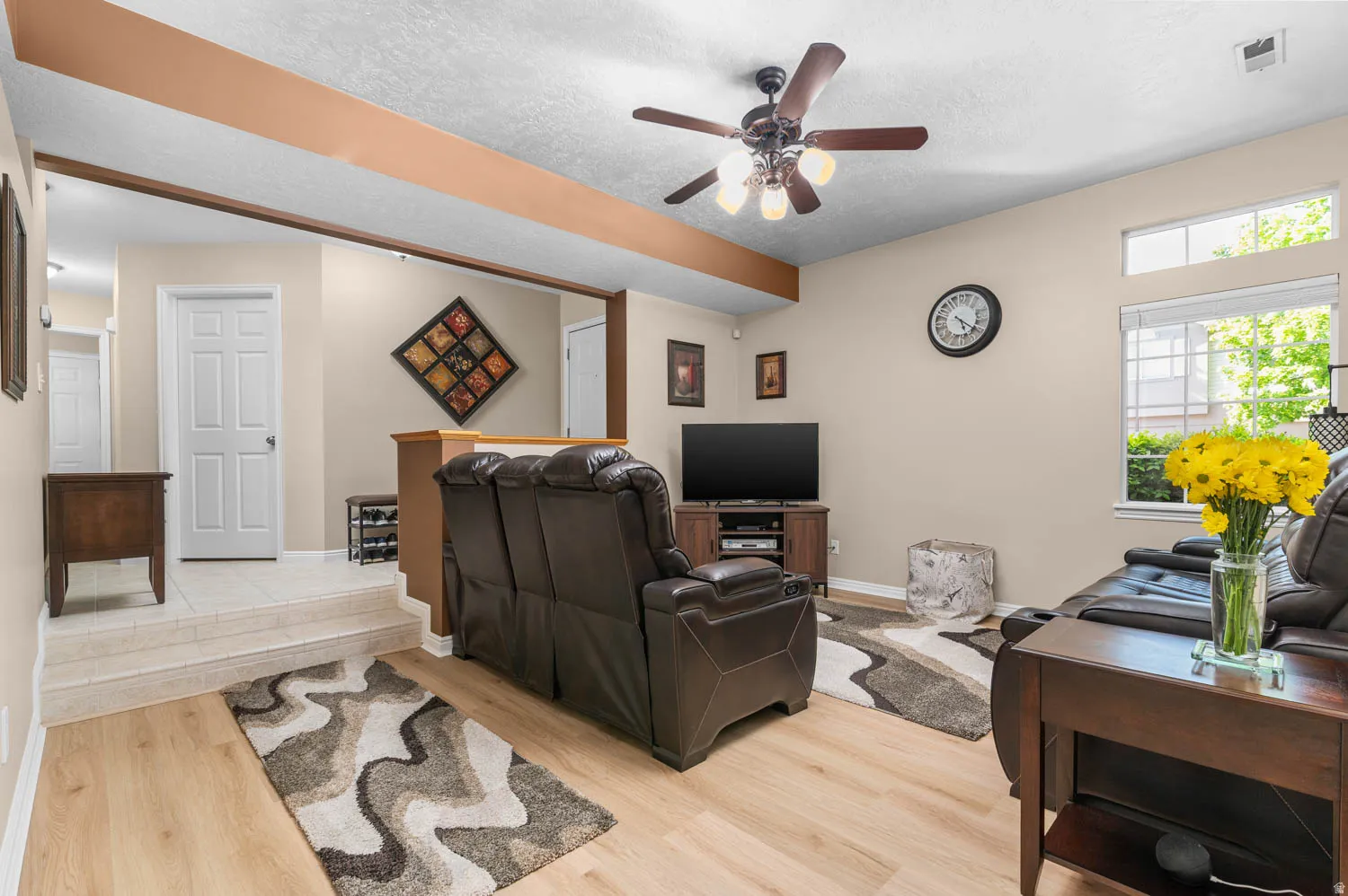 Living room with light wood-type flooring, a textured ceiling, and ceiling fan